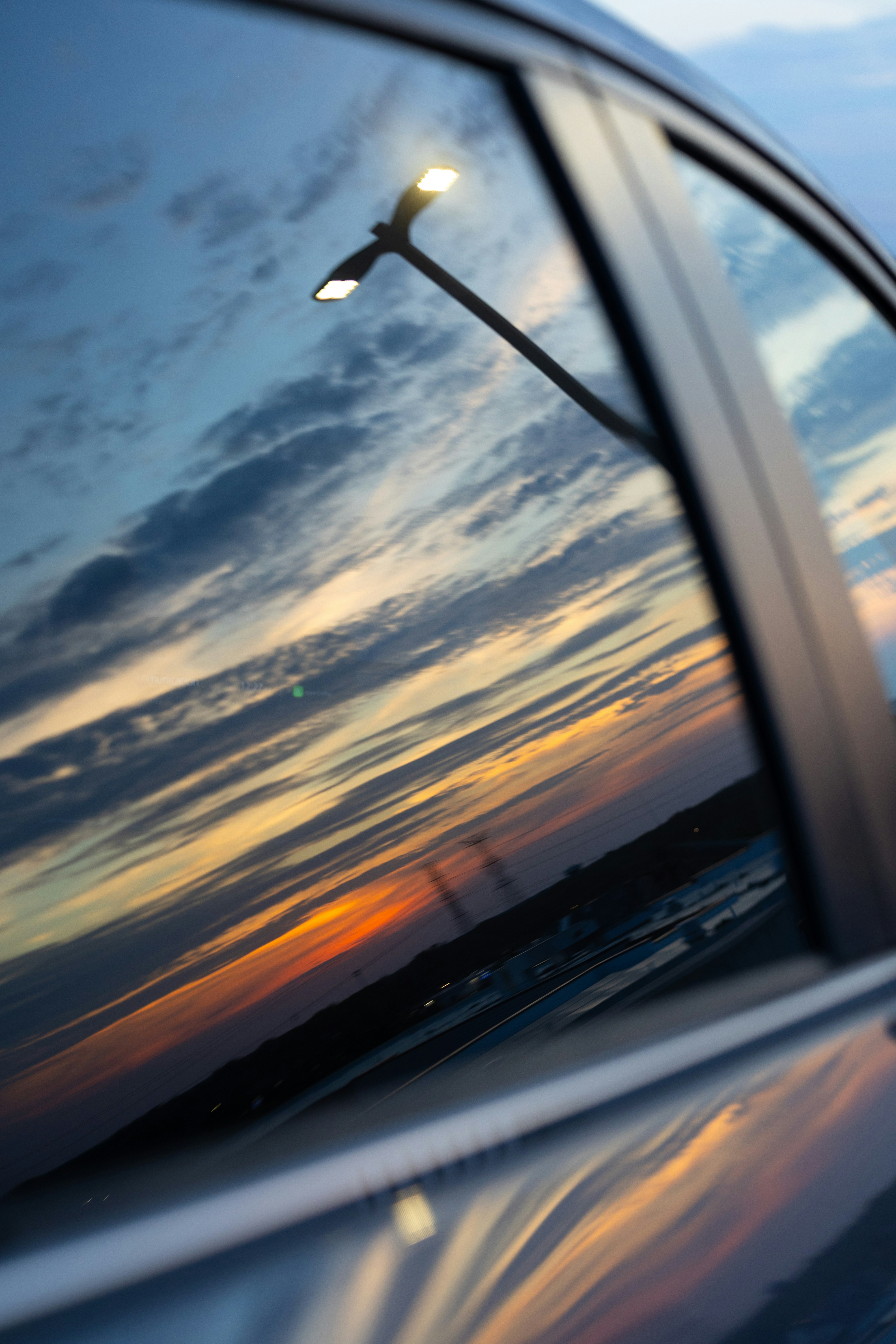 Sonnenuntergangshimmel und Straßenlicht spiegelten sich in einem Autofenster.