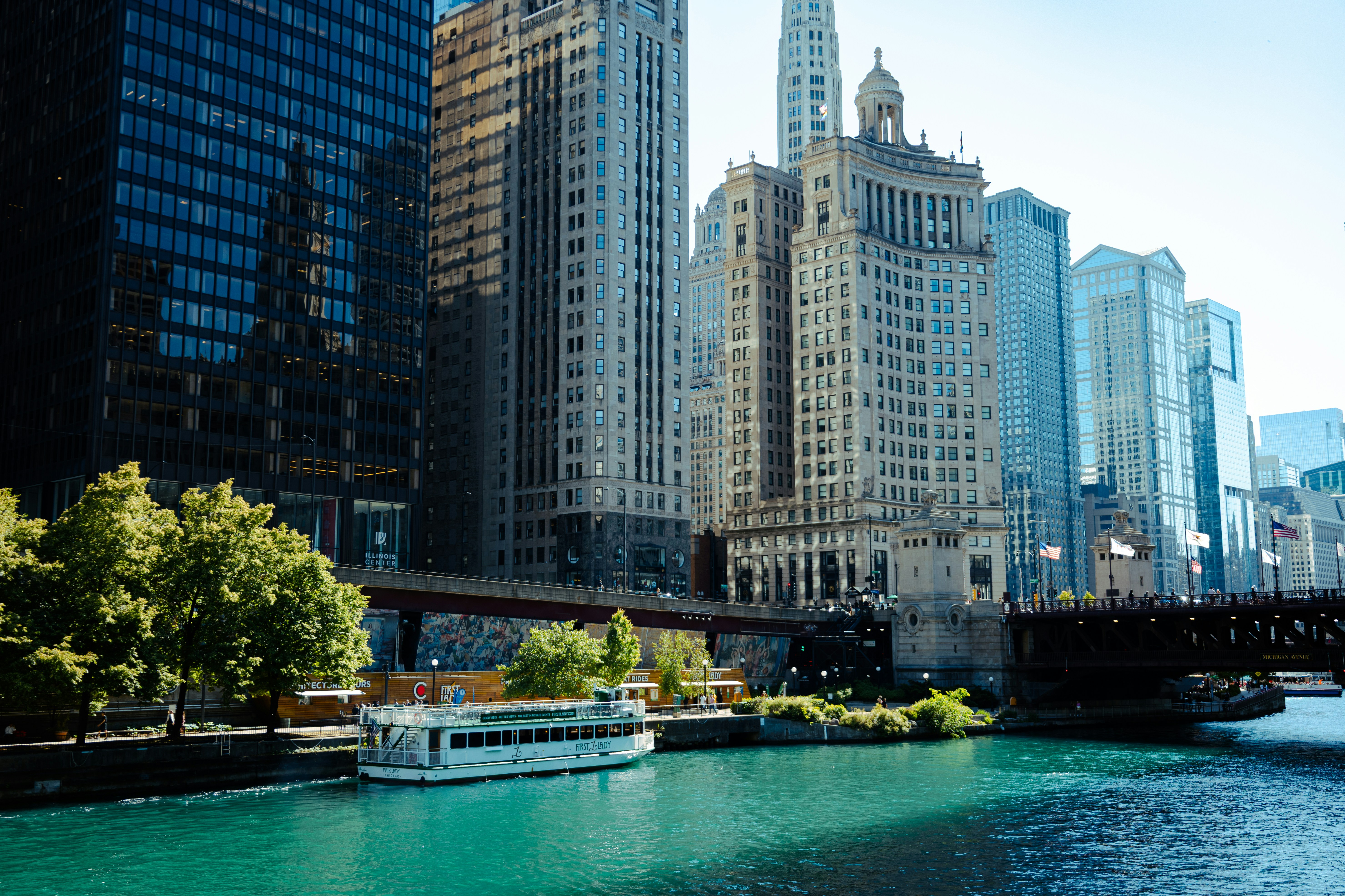 Tall city buildings line a vibrant river with a boat