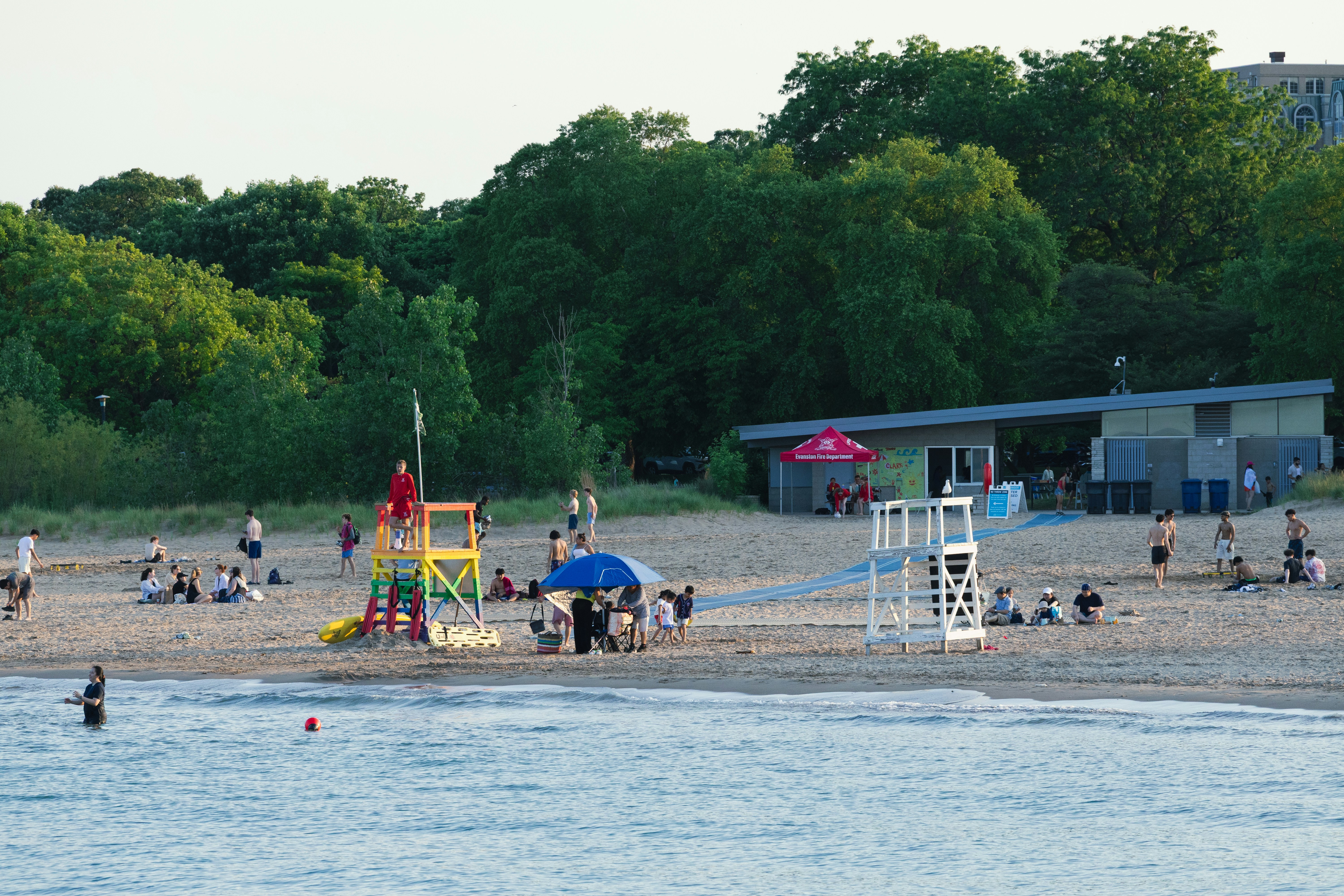 People enjoying a sandy beach with a lifeguard stand