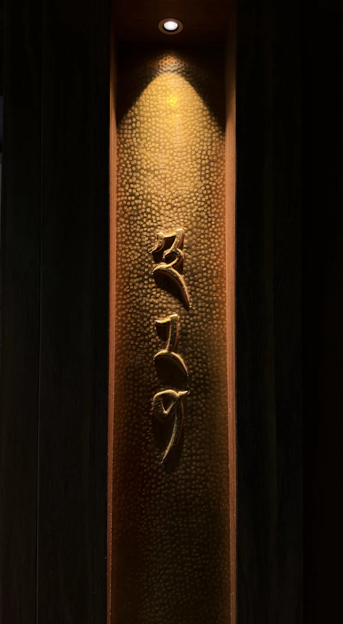 Gold script lettering hand-cut onto a hammered metal panel