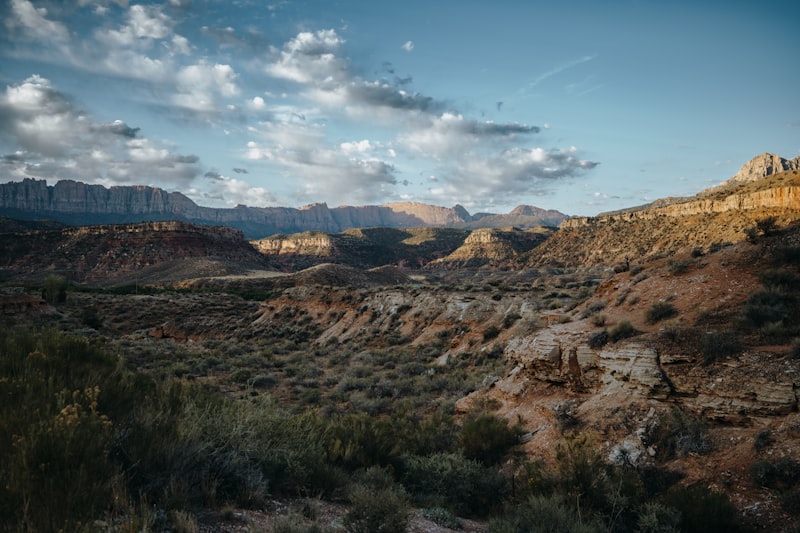 Sunlit desert mountains and valleys under a partly cloudy sky.