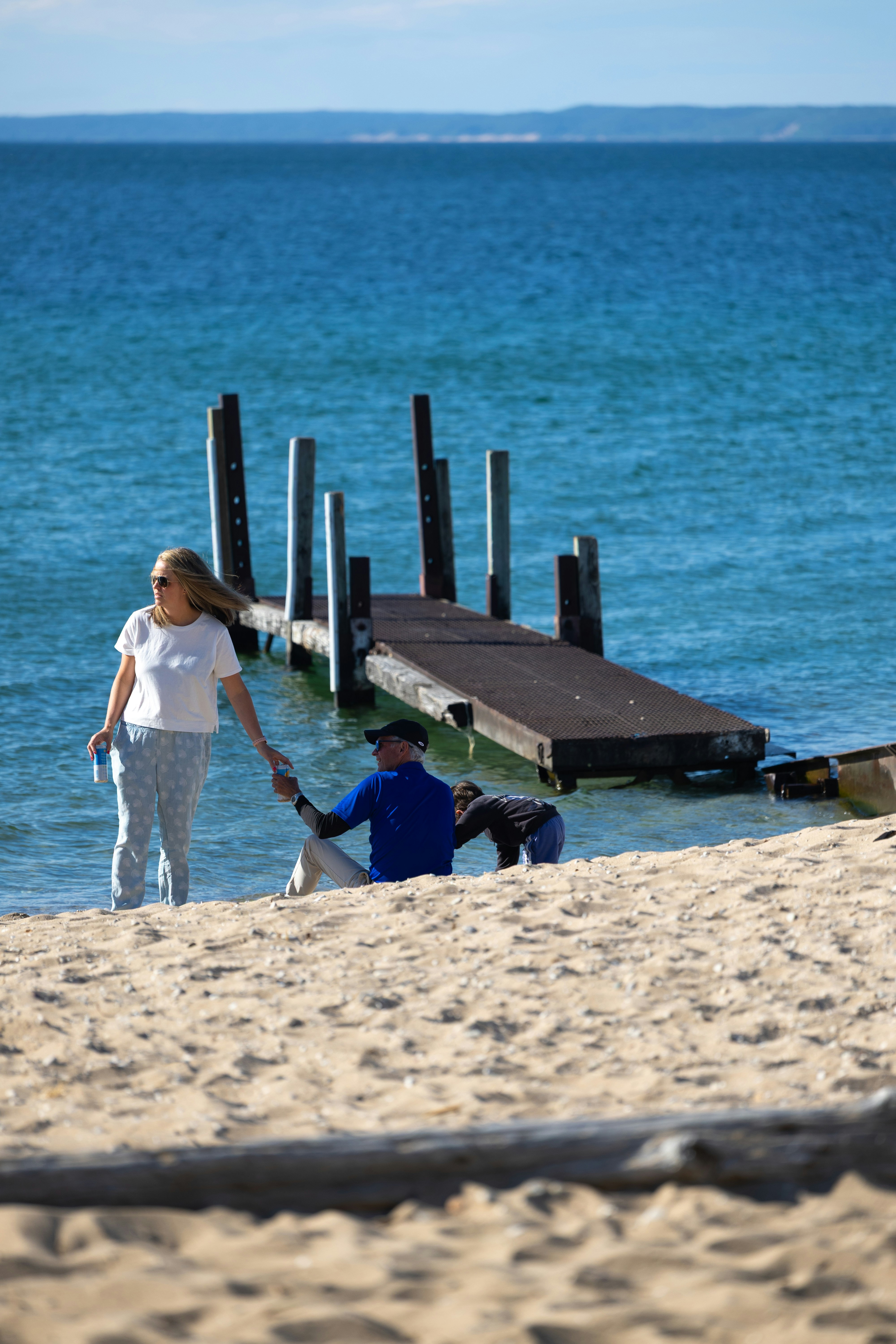 Woman and man on sandy beach with a wooden dock