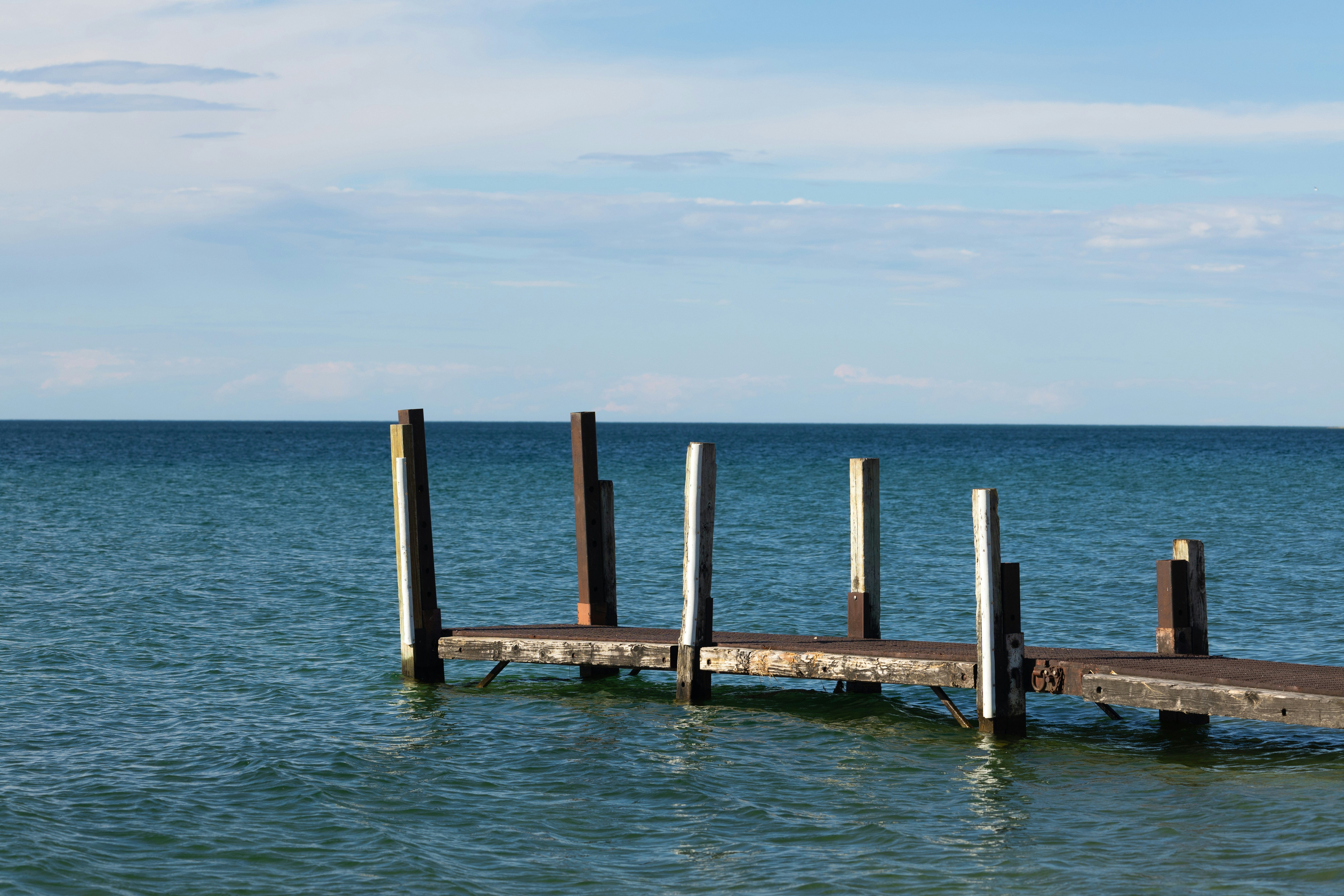 Viejo muelle de madera en aguas azules tranquilas bajo cielo nublado ...