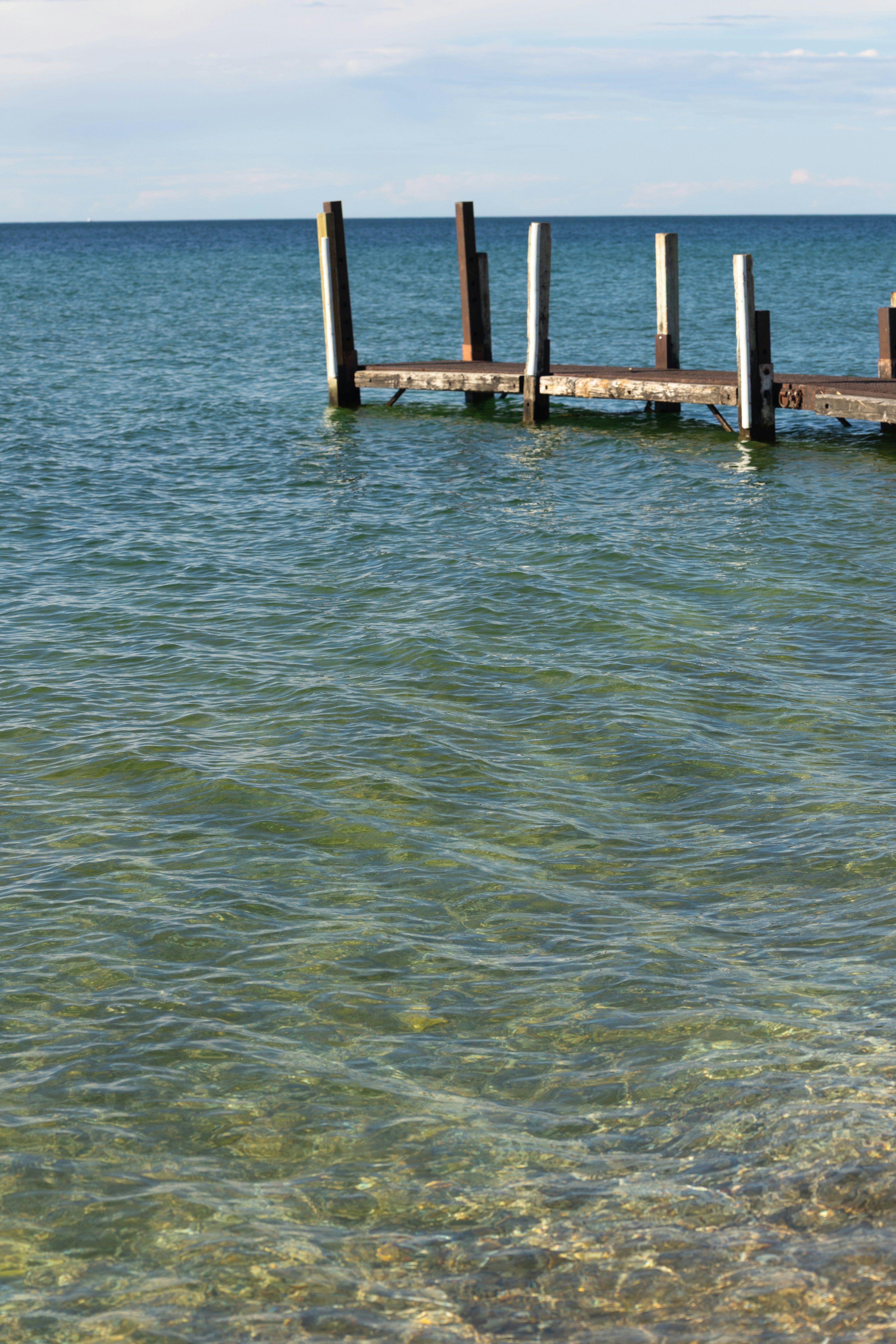 Antiguos postes de muelle de madera se alzan en aguas claras del lago ...