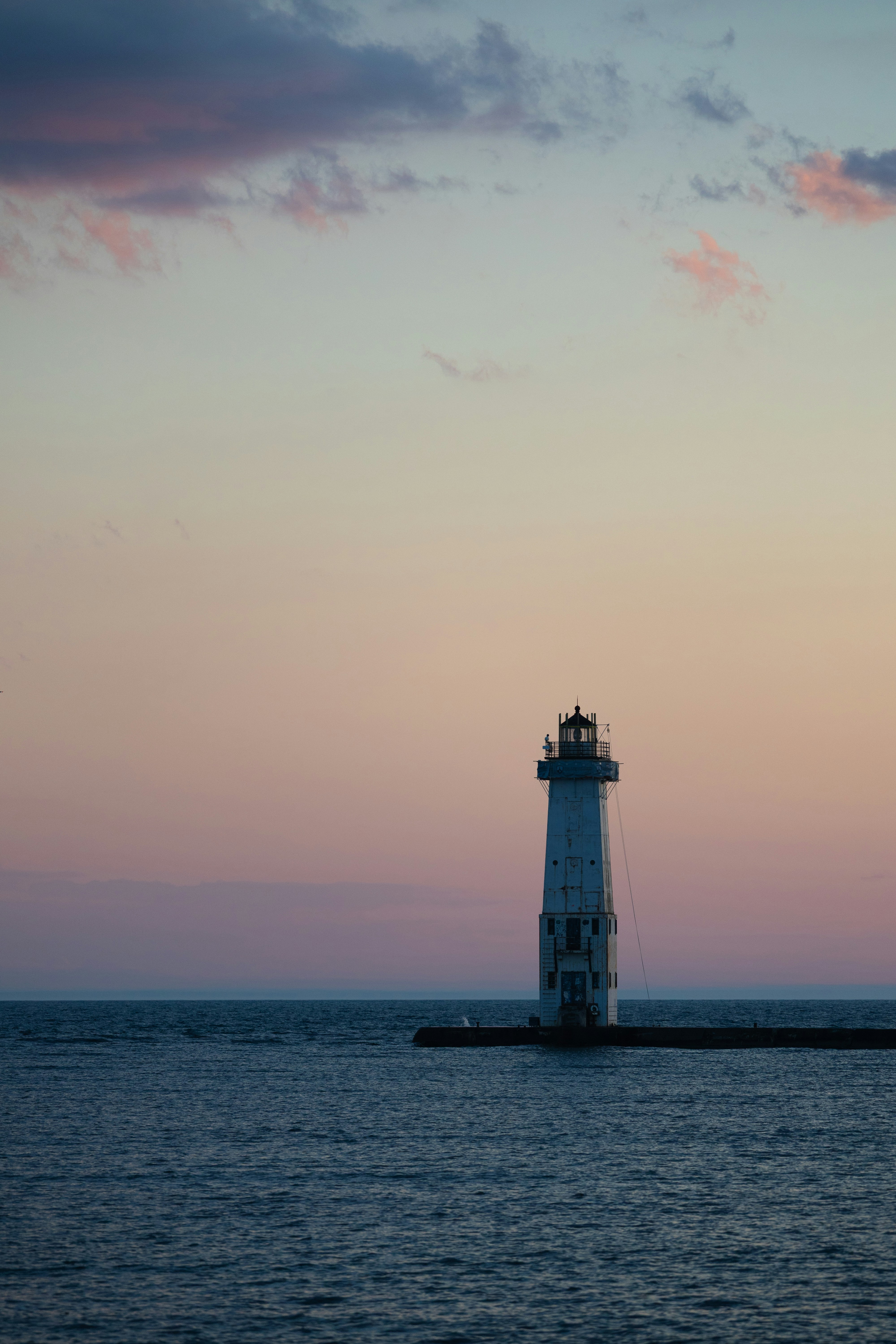 Faro su un molo al crepuscolo con un cielo colorato.