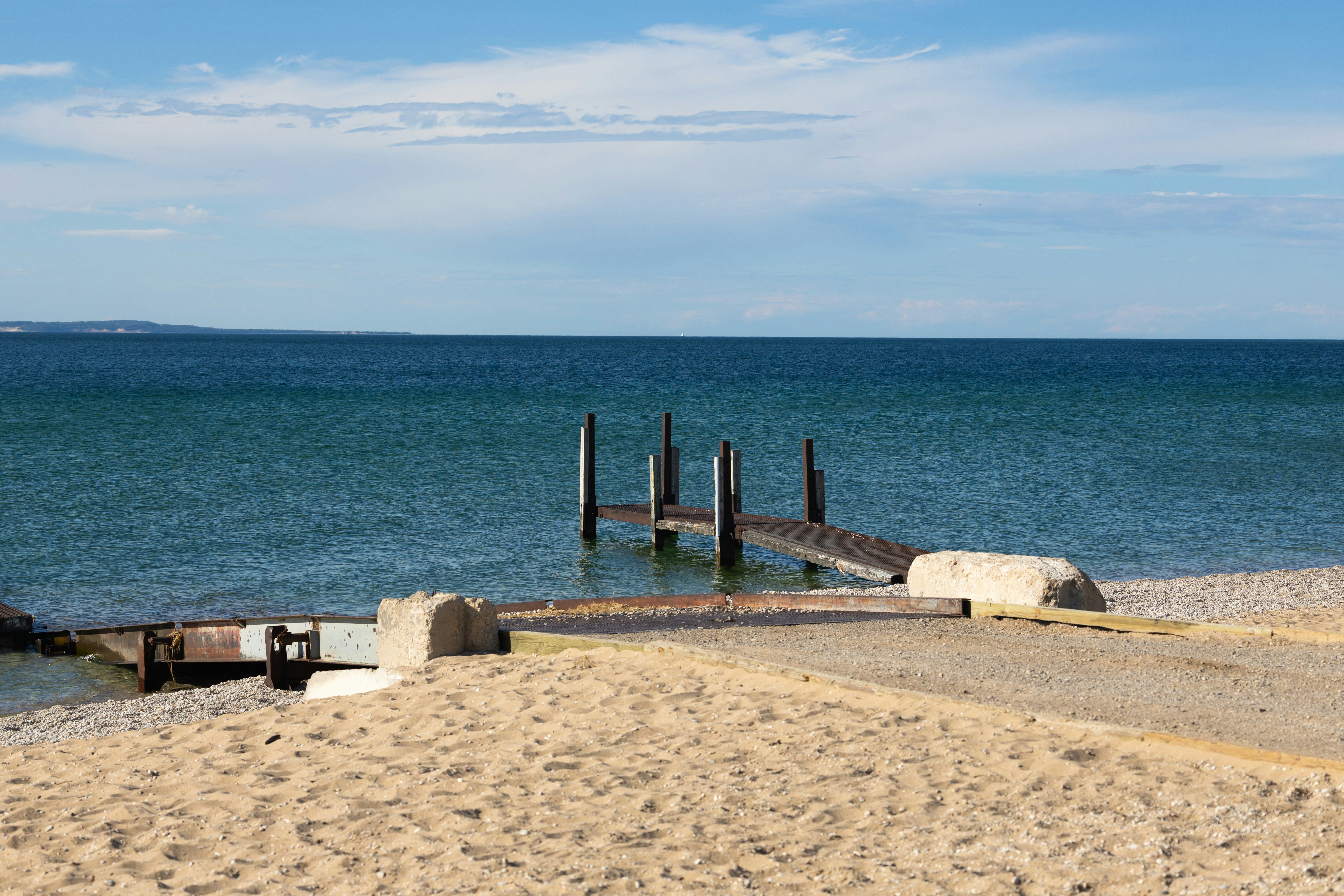 Playa de arena con un muelle de madera que se adentra en aguas azules ...