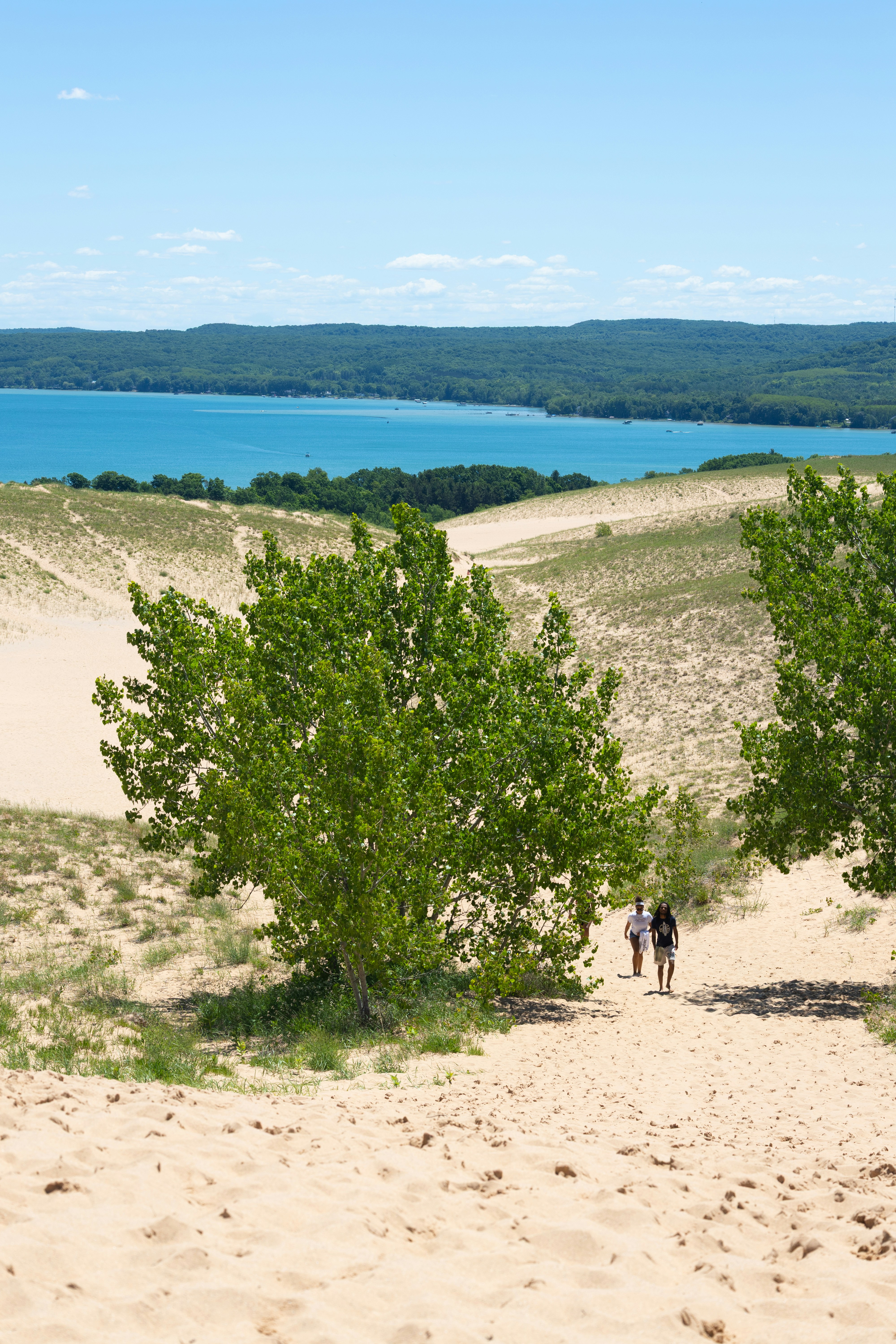 La gente camina por dunas de arena con vistas a un lago azul - Foto ...