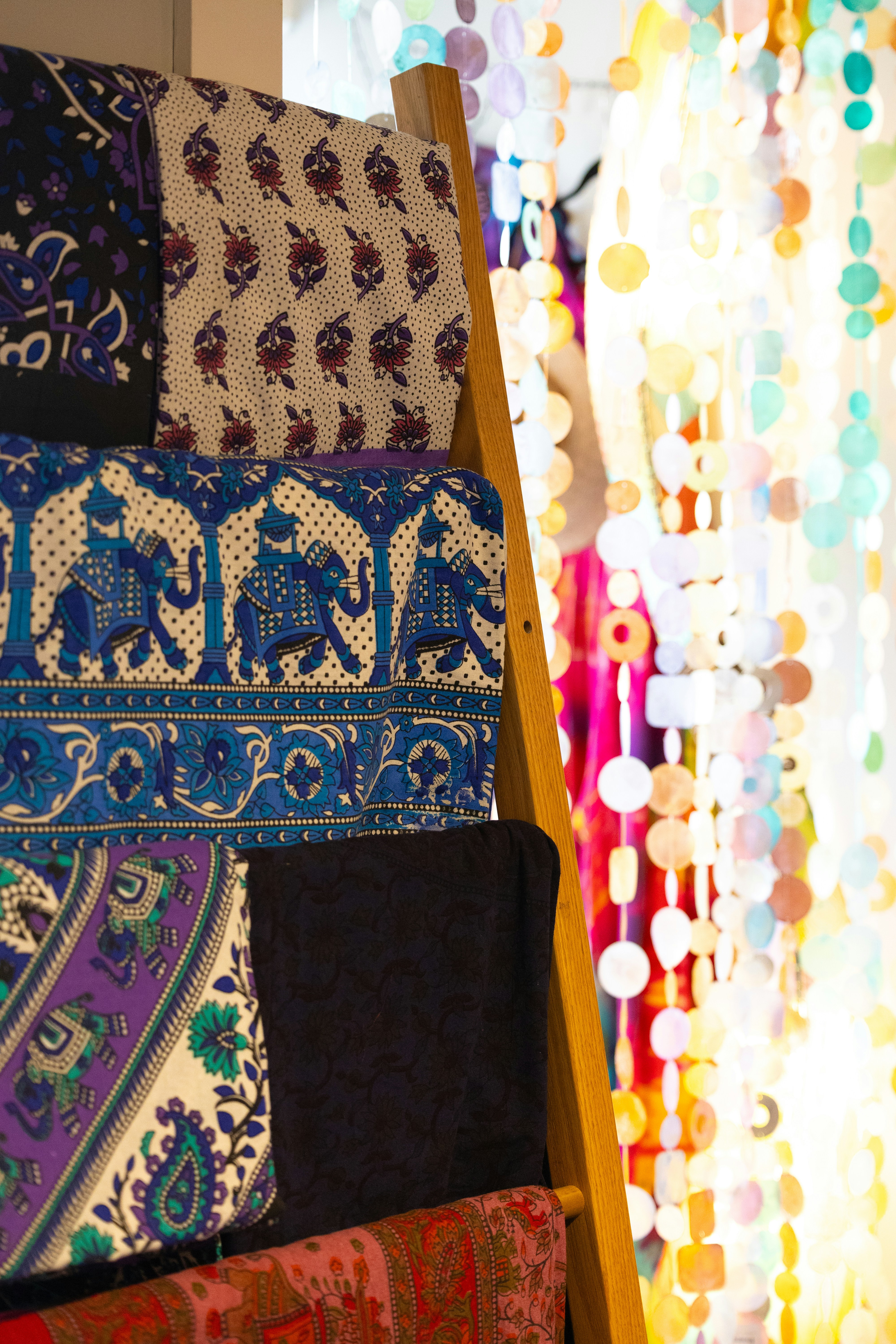 Intricate patterned fabrics on a wooden ladder display.
