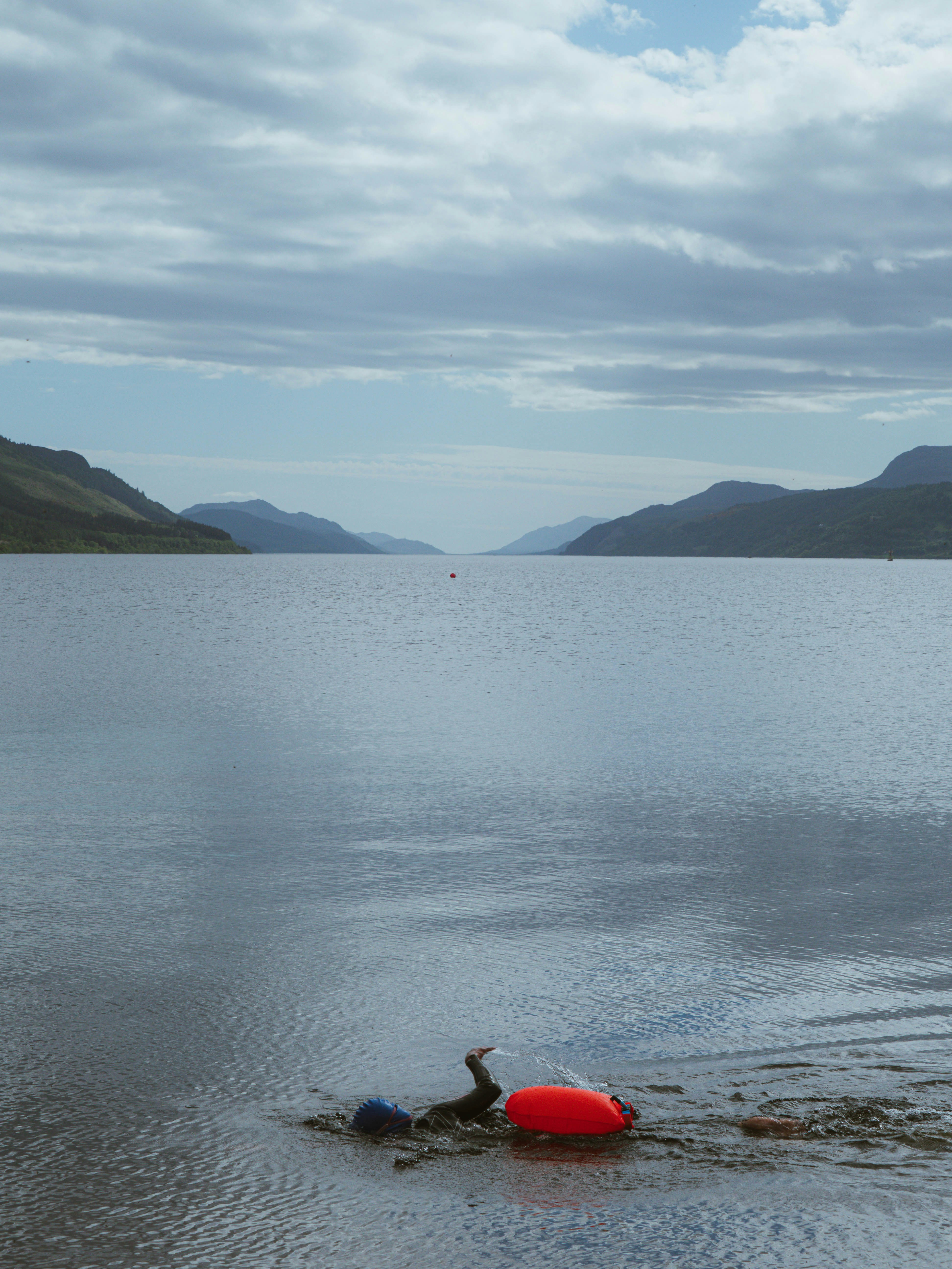 Red buoy on a calm loch with distant mountains.