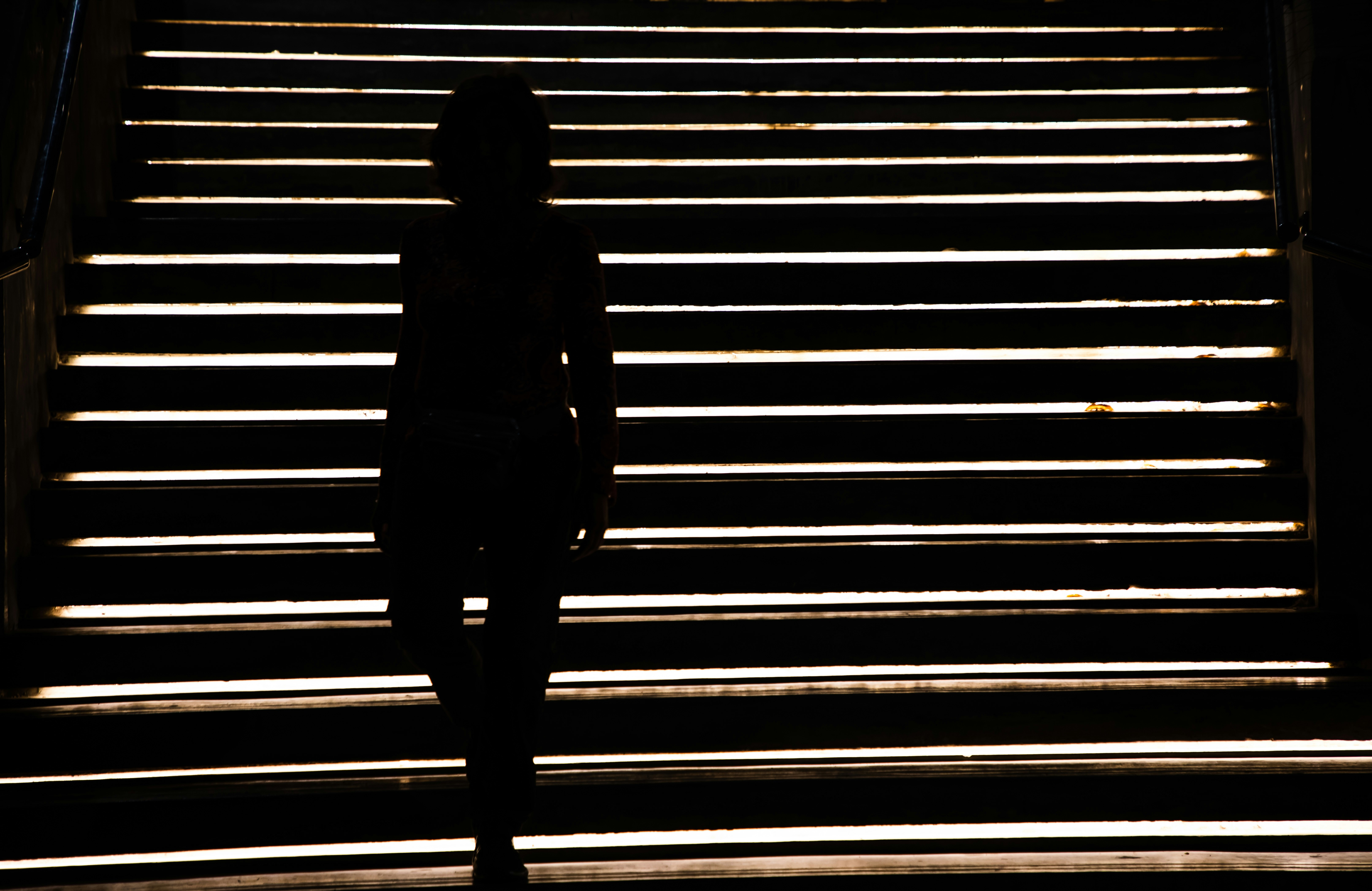La silueta de una persona sube una escalera muy iluminada