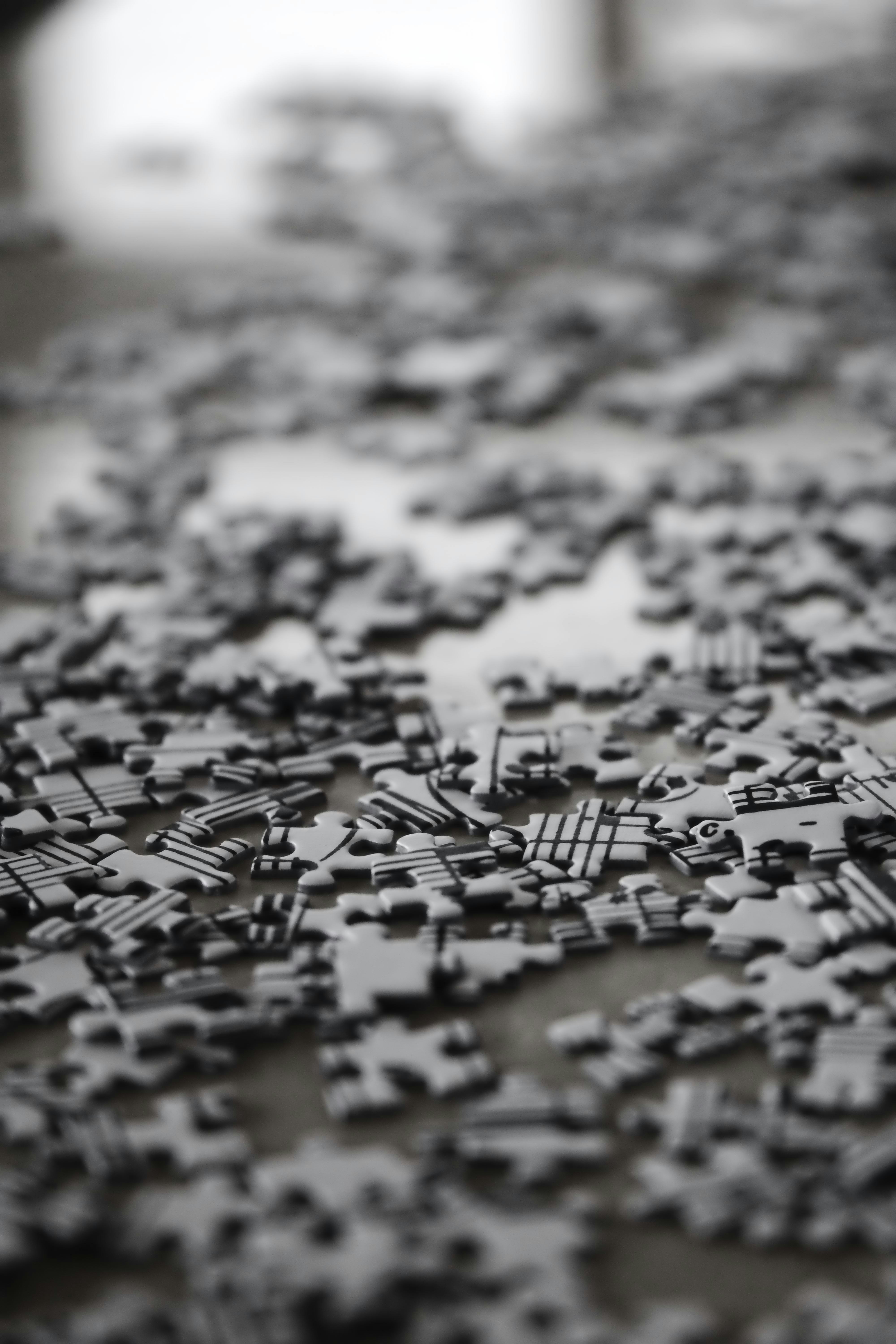 Scattered black and white puzzle pieces on a surface