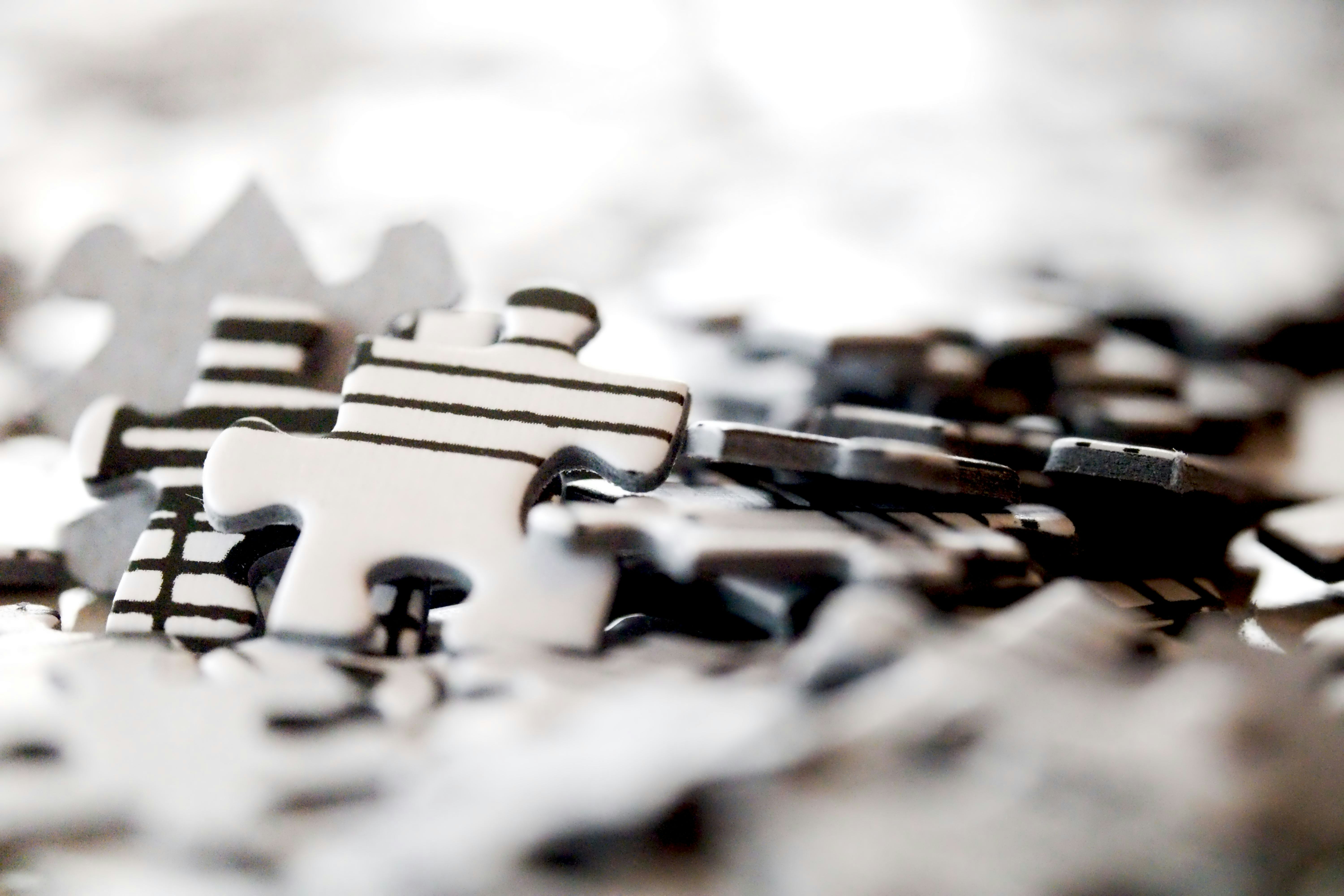 Scattered black and white jigsaw puzzle pieces