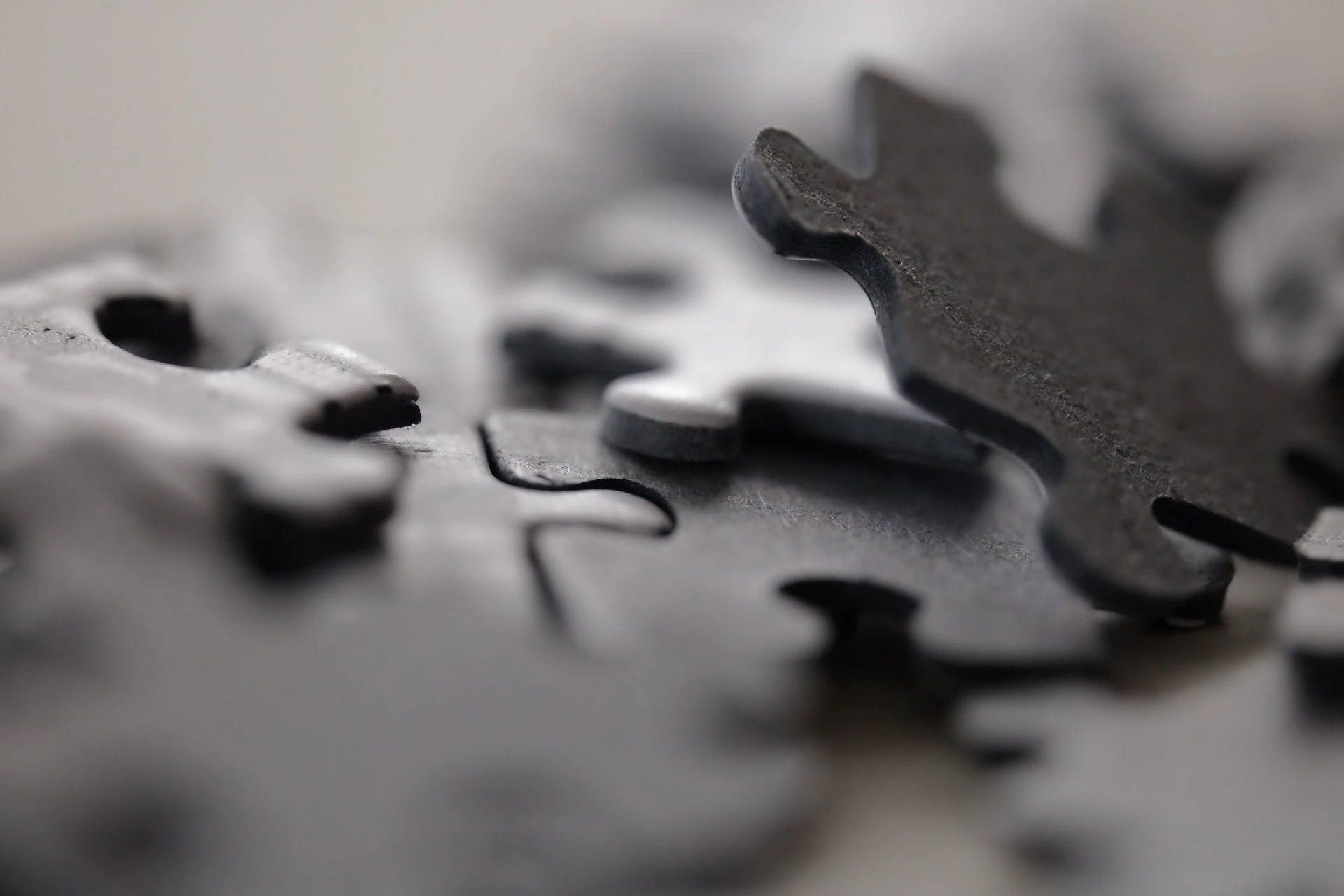 Scattered dark gray puzzle pieces with one piece slightly raised.