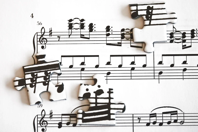 Scattered puzzle pieces with musical notes on sheet music