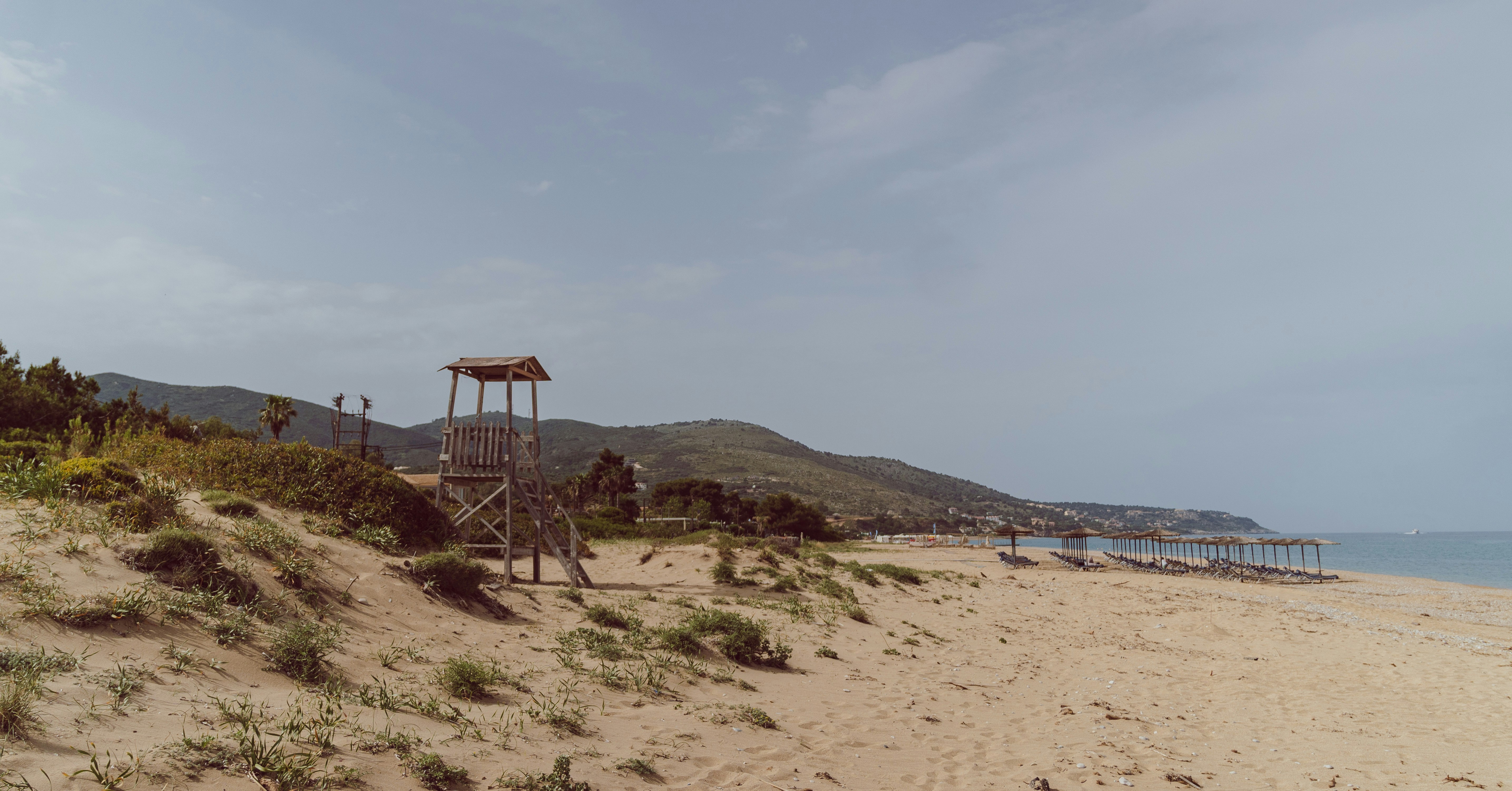 Lifeguard tower on sandy beach with coastal hills