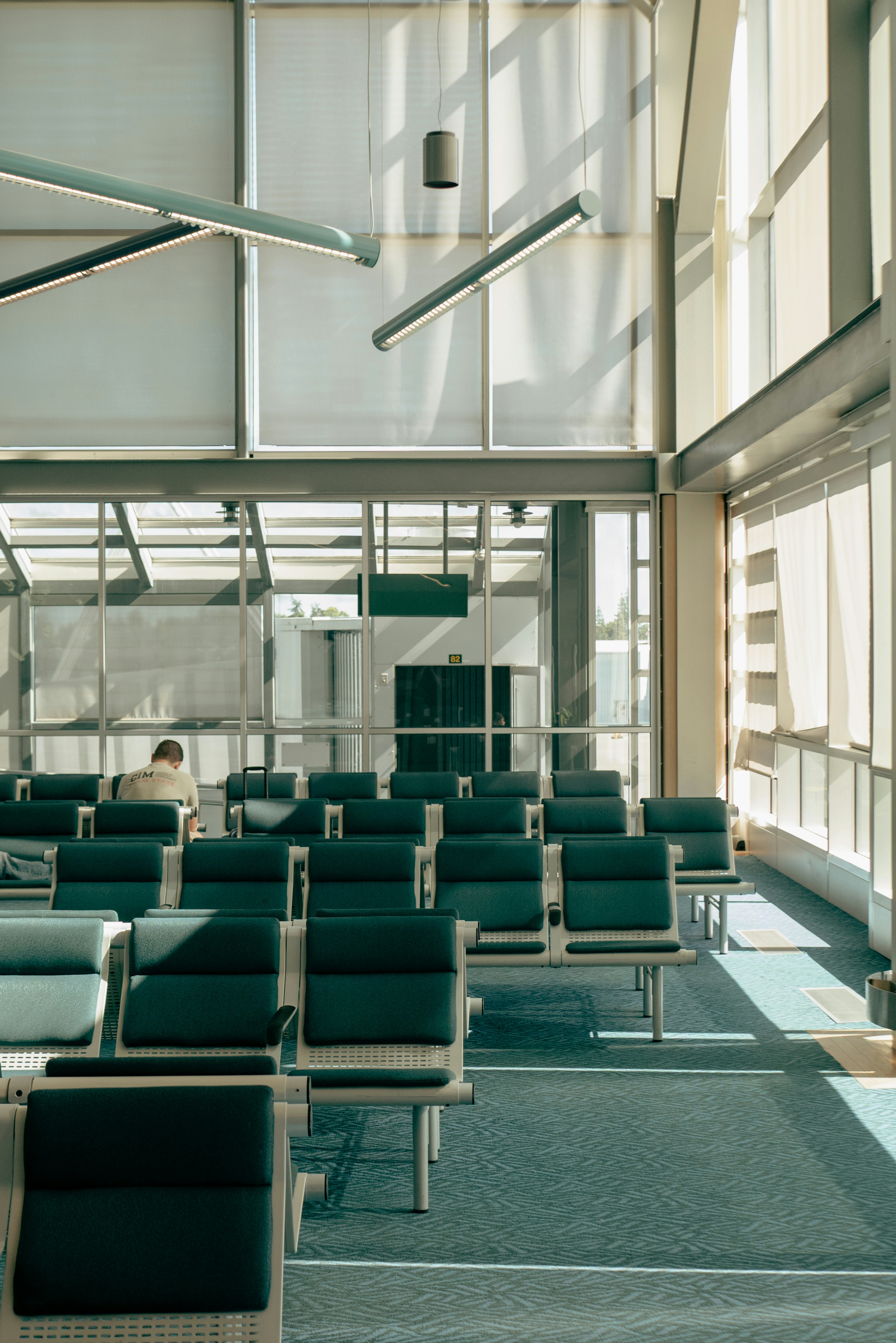 Modern airport waiting area with empty seats and sunlight.