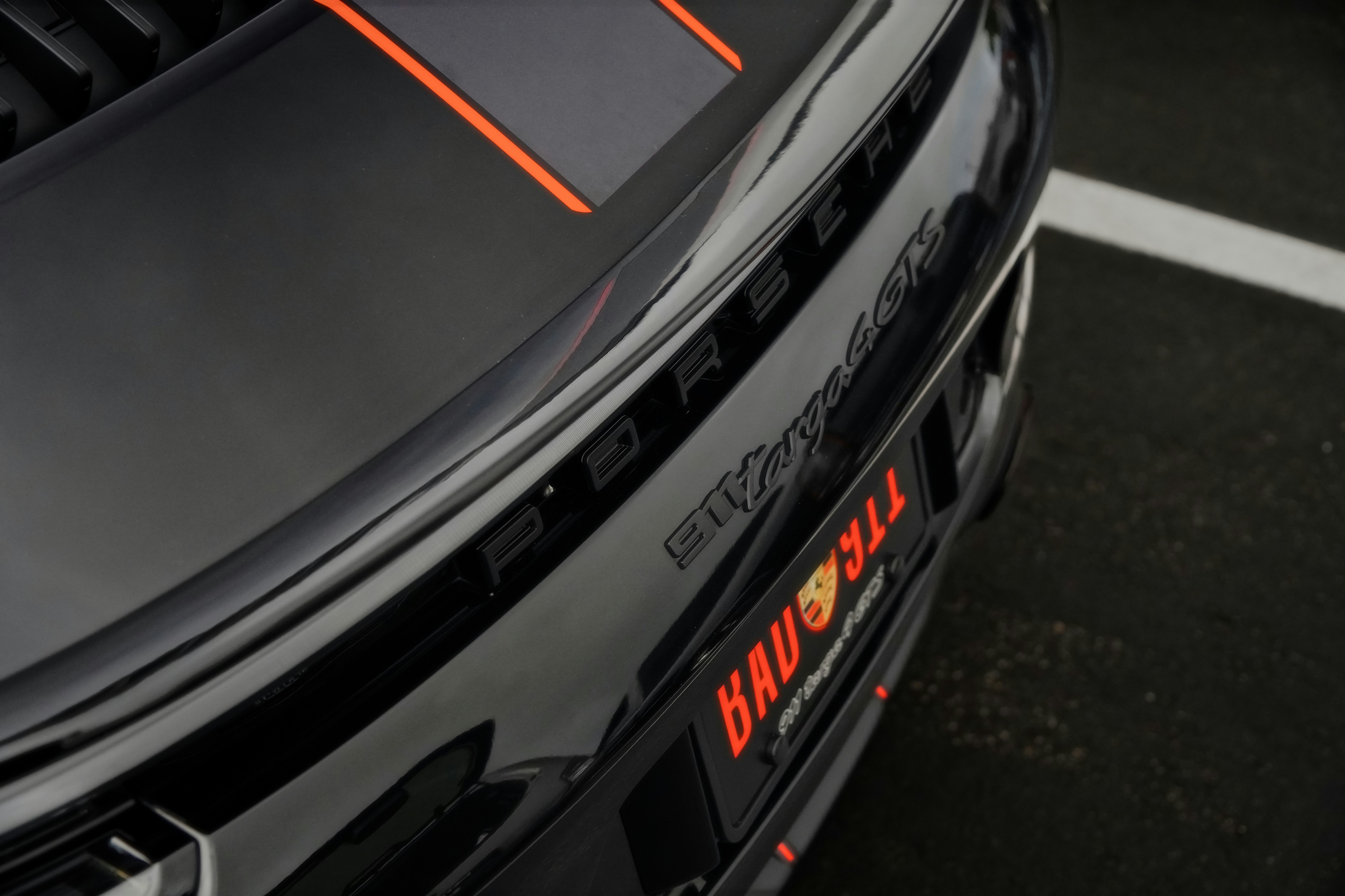 Black porsche car with orange racing stripes.