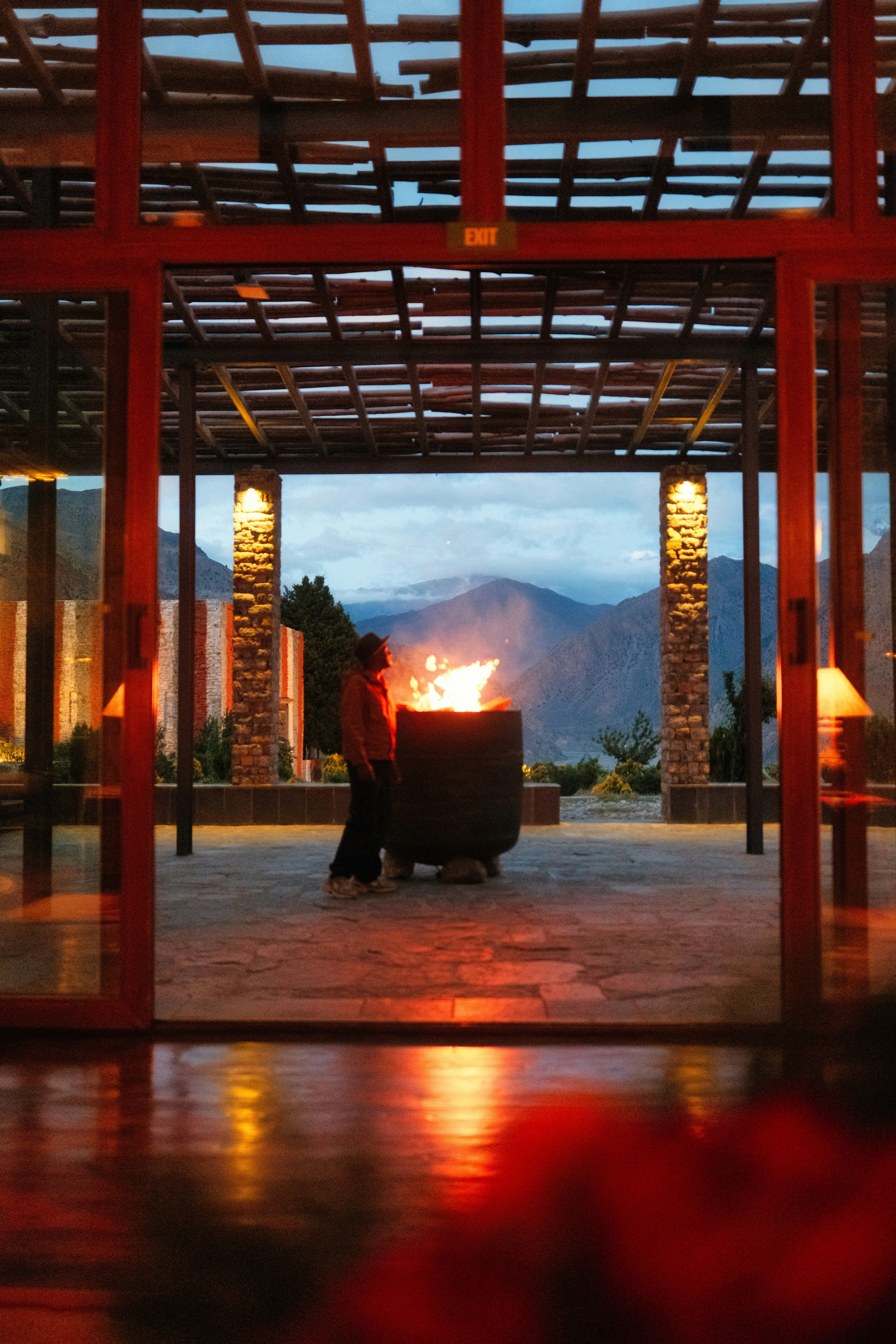 Person by a warm fire pit overlooking mountains at twilight