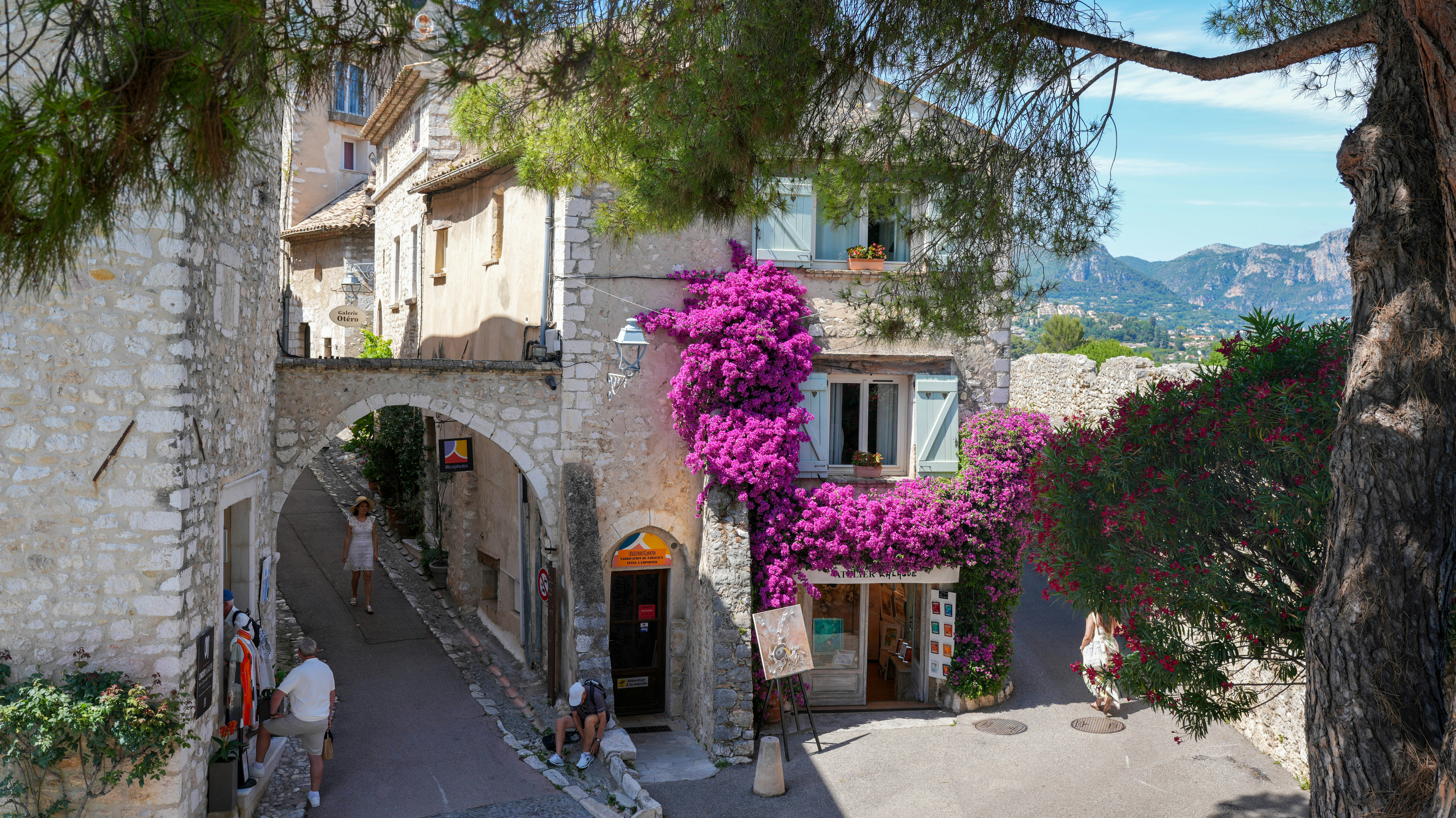 A charming european village street with vibrant purple bougainvillea | Houfy — Book Direct