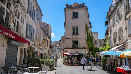 Rua com mesas ao ar livre e fachadas antigas em Arles, Provence