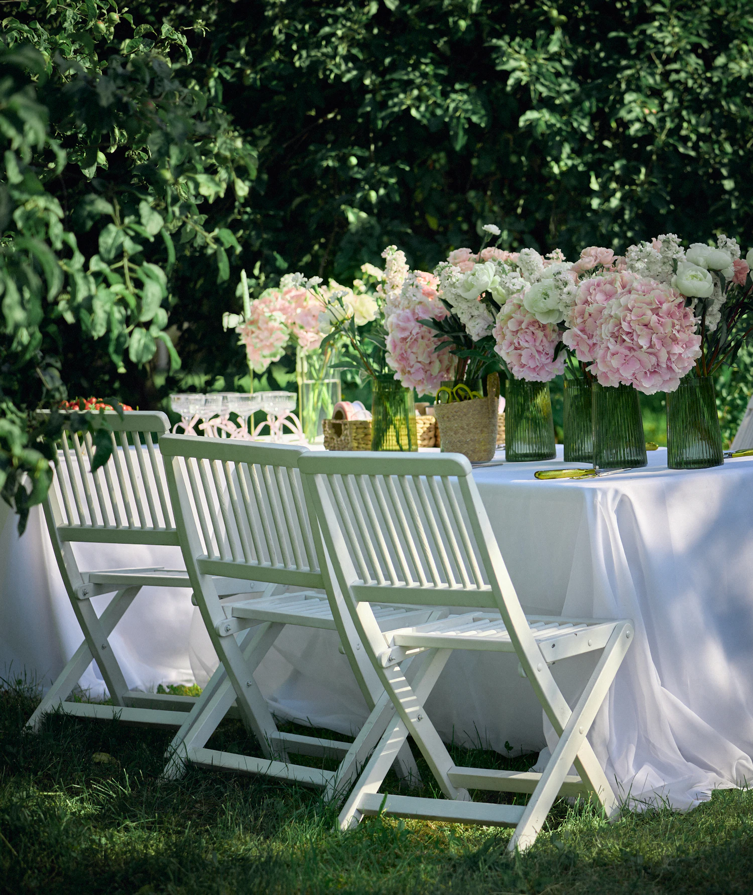 Light outdoor table setting with flowers, dinnerware and dining chairs