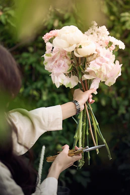 Person trimming stems of a pink and white flower bouquet