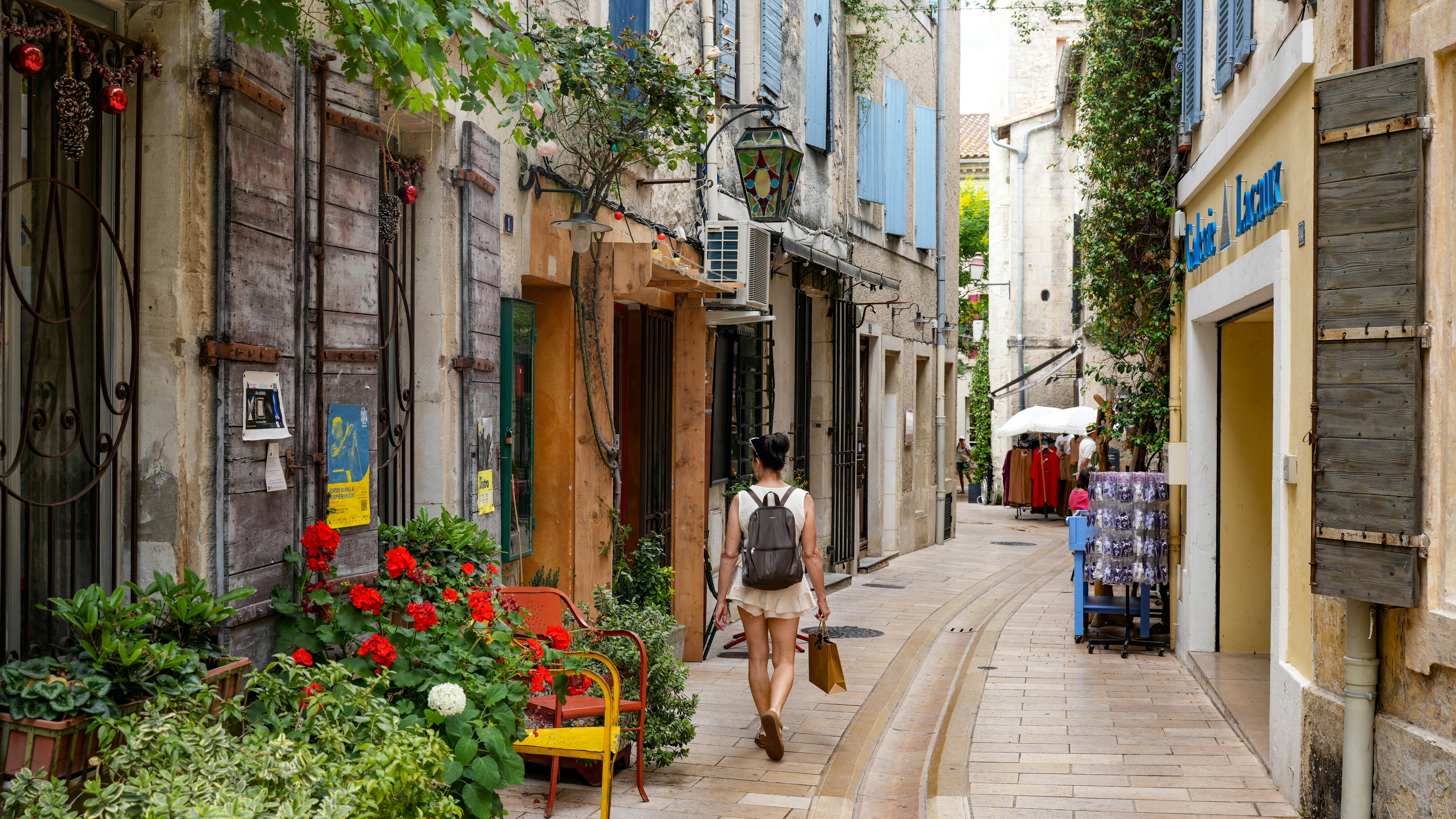 A woman walking down a narrow, charming european street.
