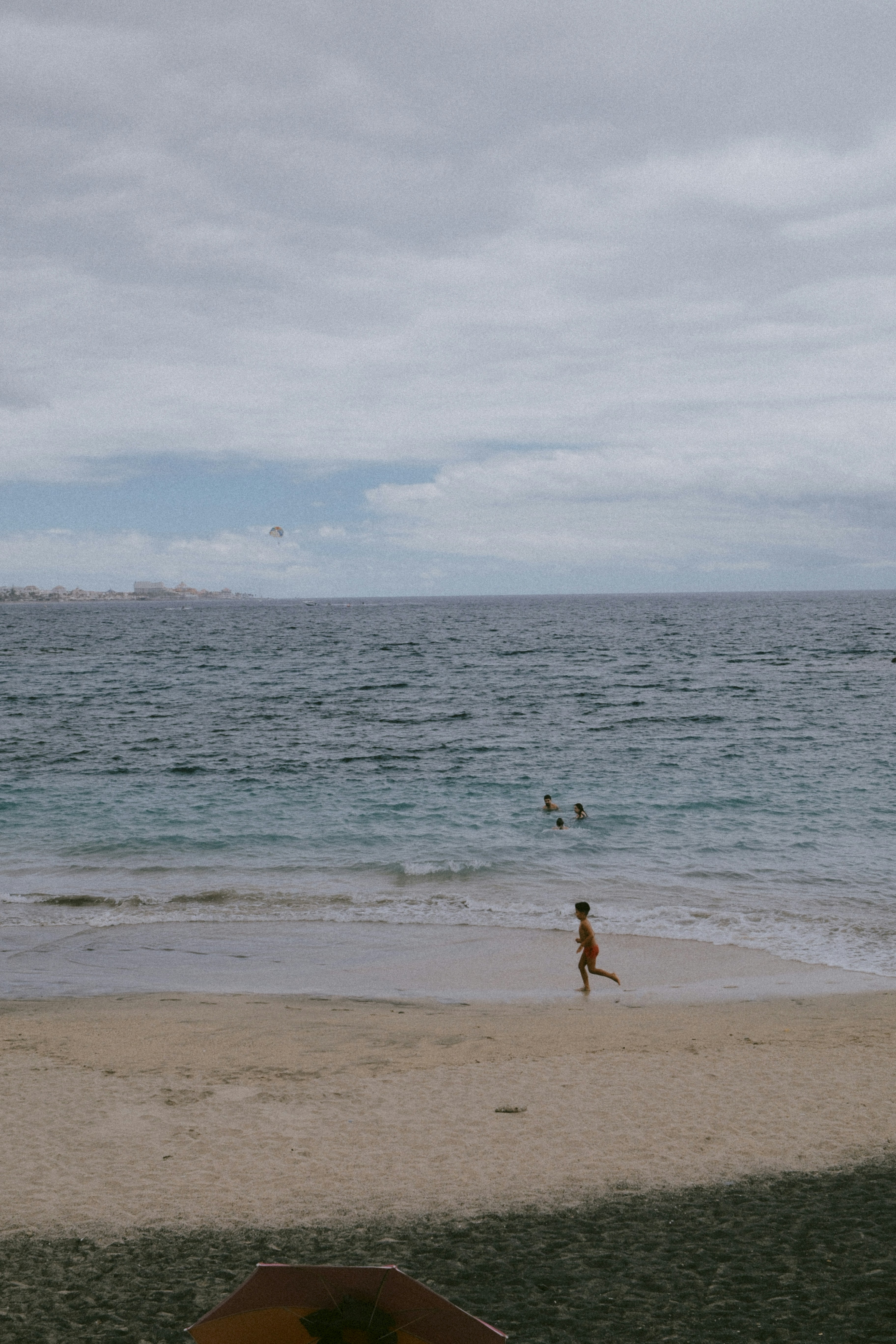 Child running on sandy beach by the blue ocean.
