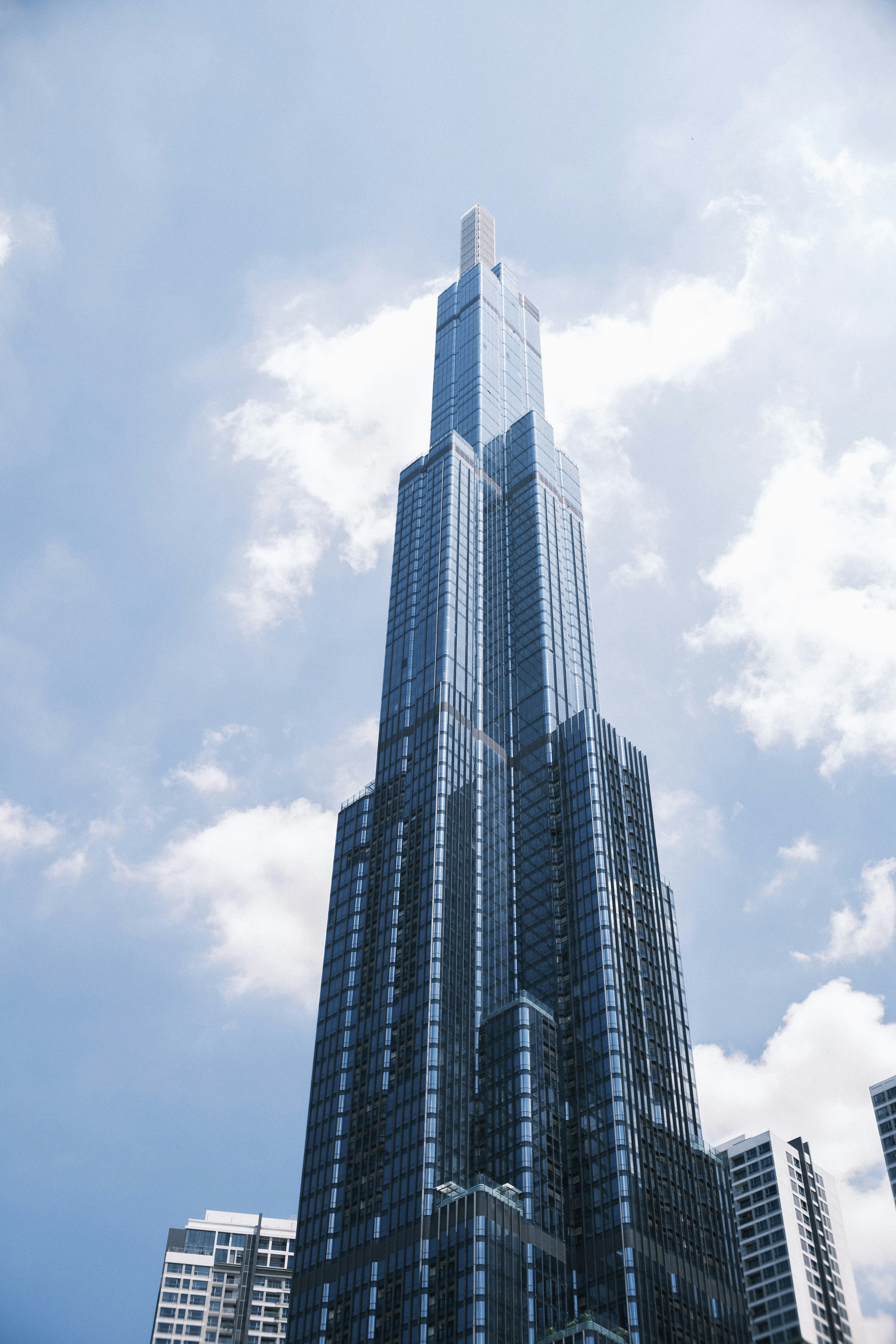 A towering modern skyscraper against a cloudy blue sky