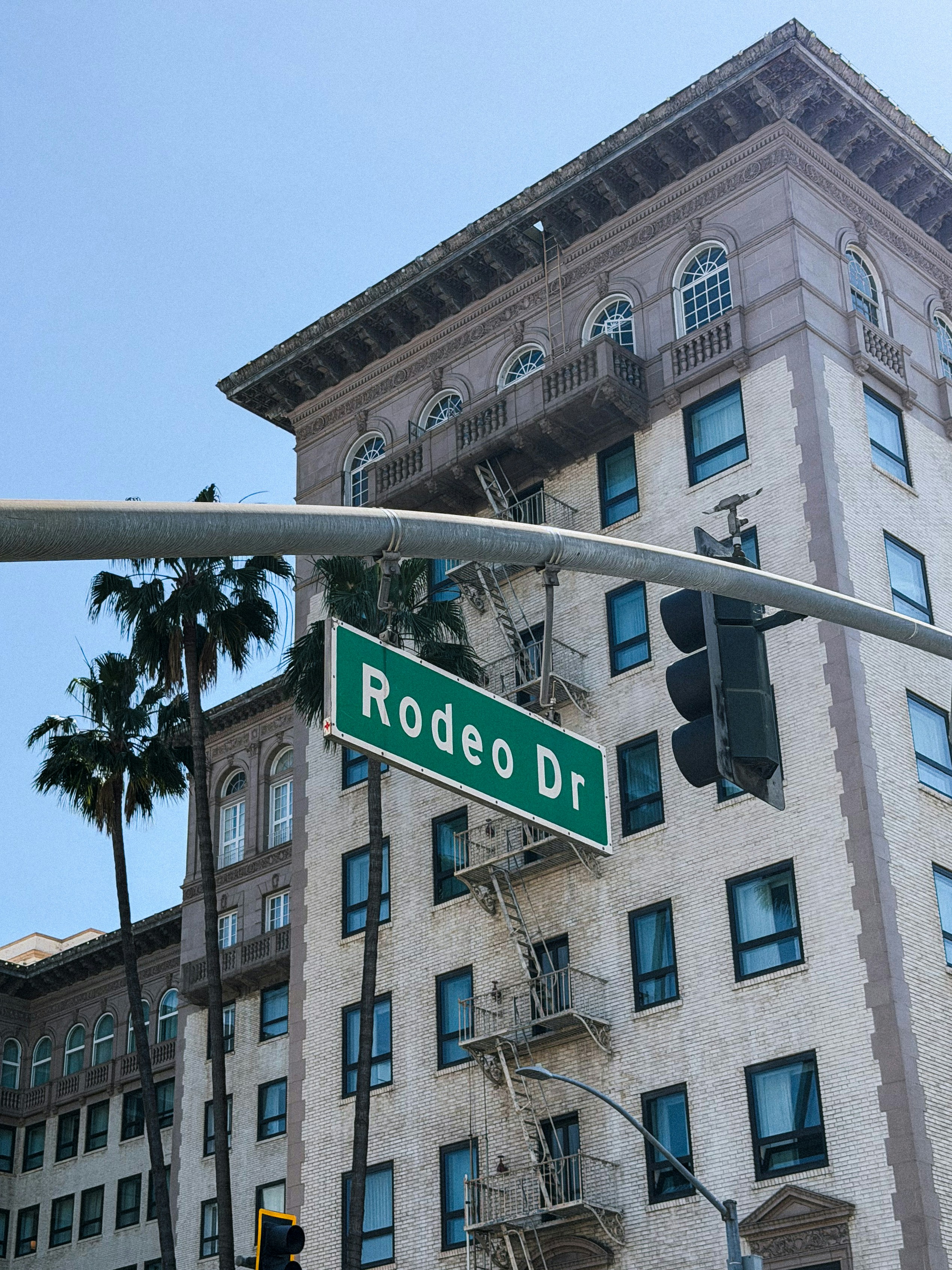 Rodeo drive street sign against a building and palm trees