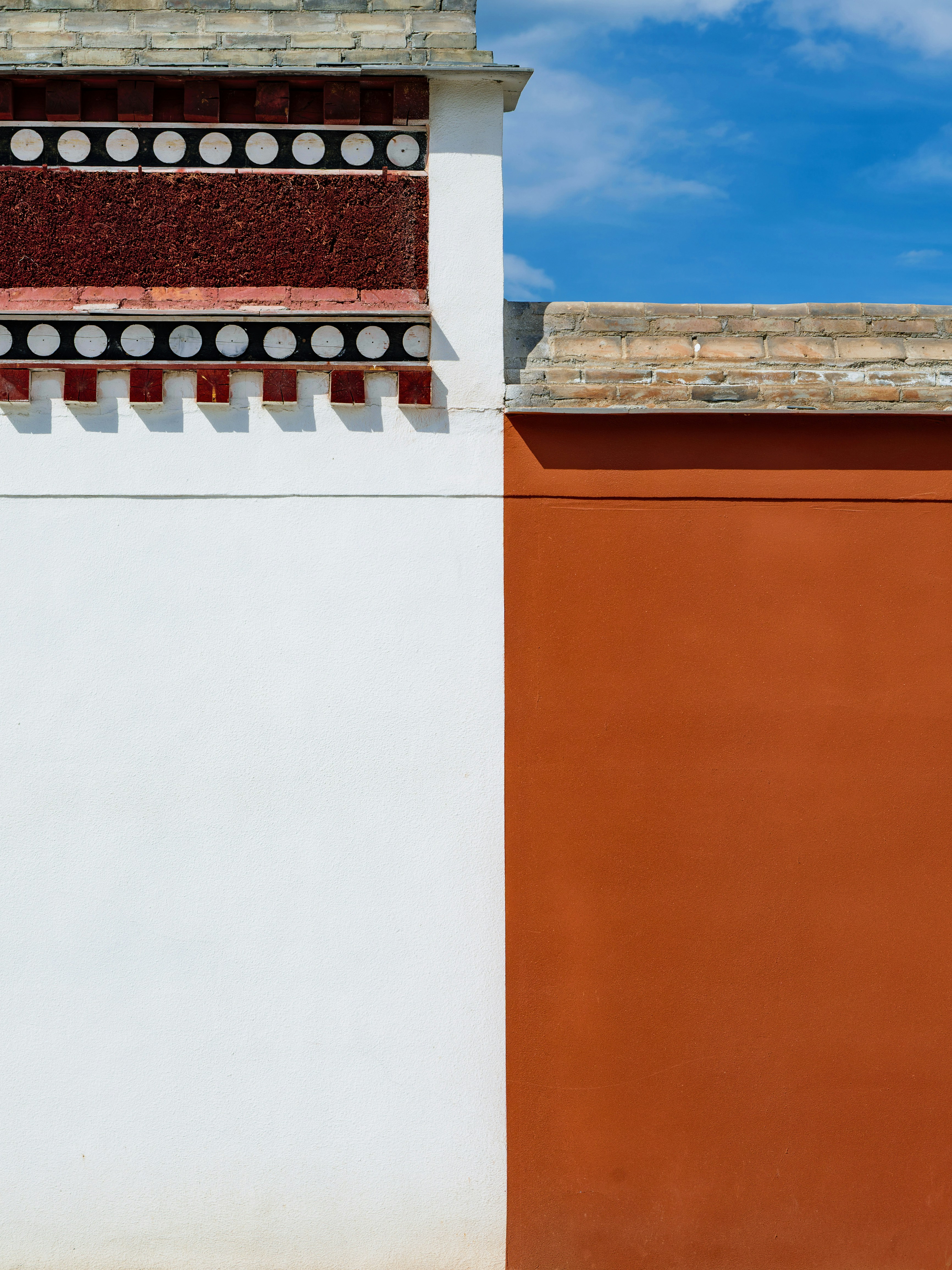 Decorative white and red wall against a clear blue sky.