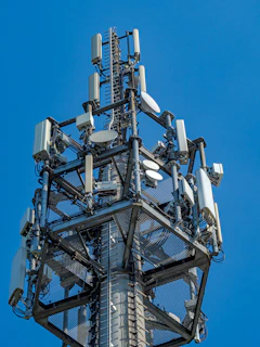 A tall telecommunications tower with many antennas against blue sky.