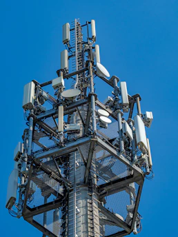 A tall telecommunications tower with many antennas against blue sky