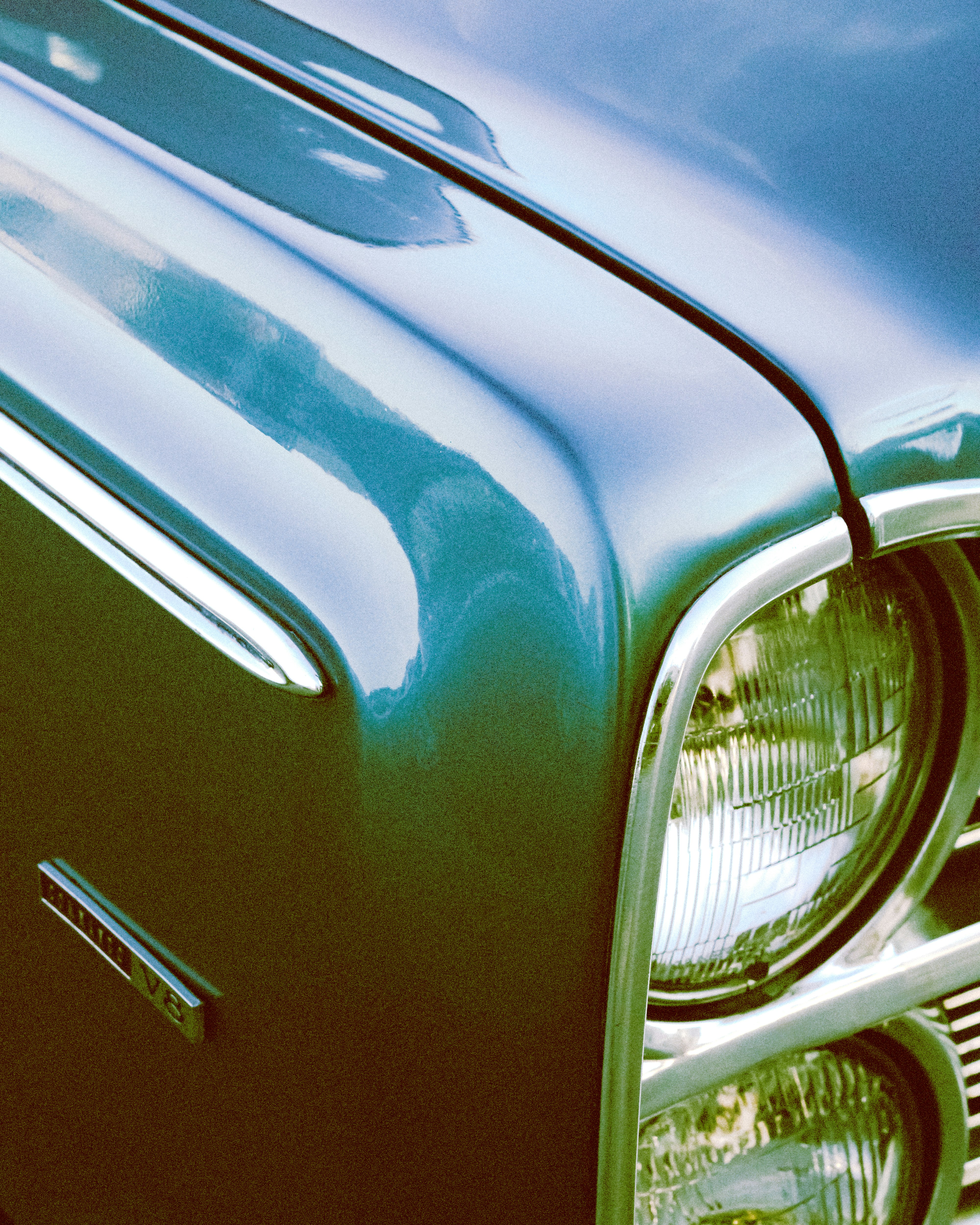 Vintage teal car's headlight and fender.