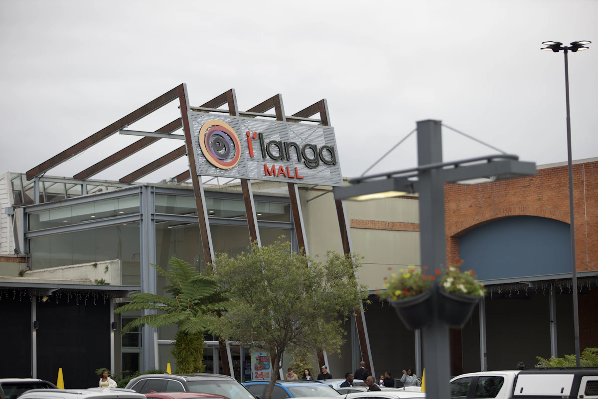 Exterior of I'langa Mall with parked cars and a tree
