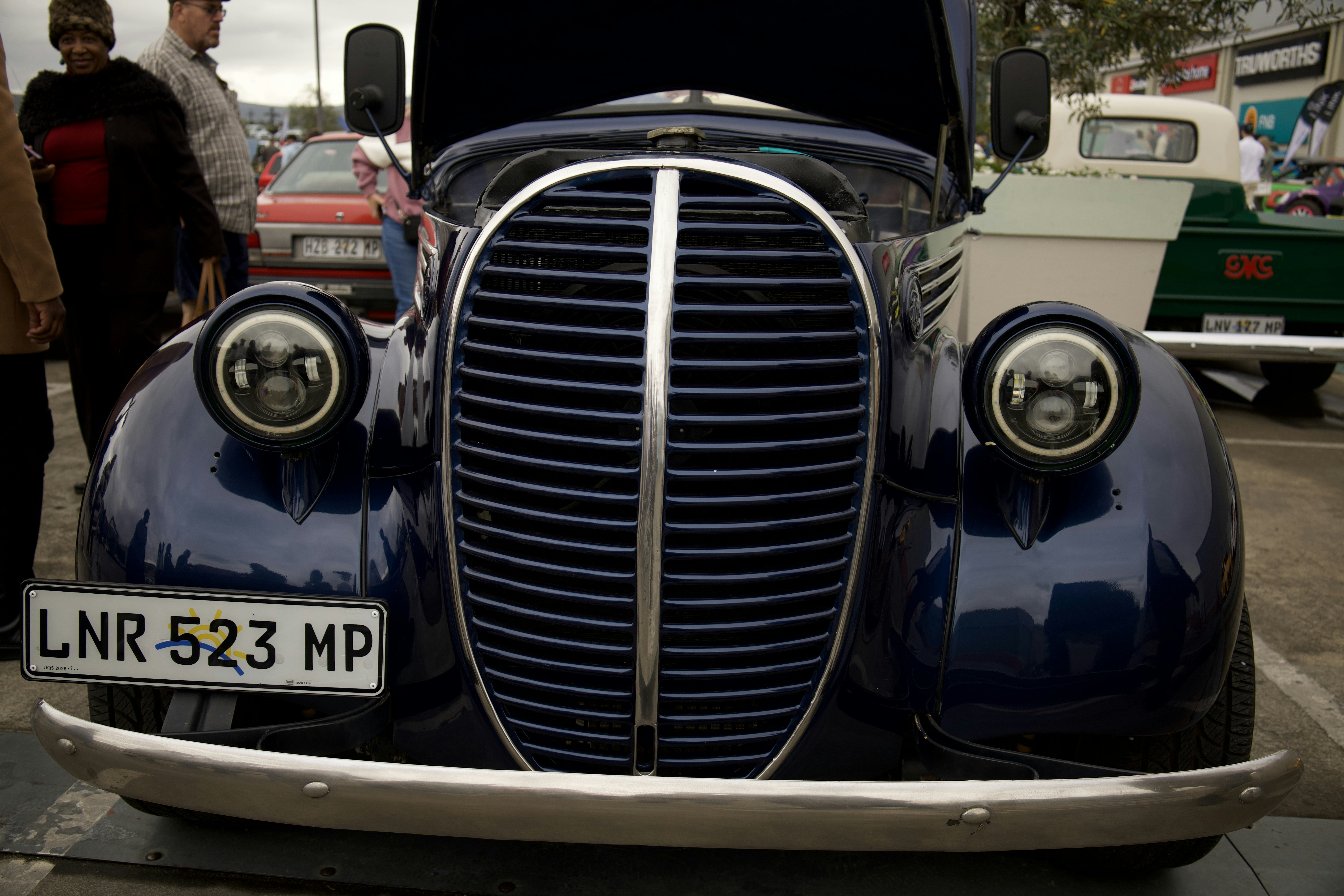 A vintage dark blue car with an open hood.