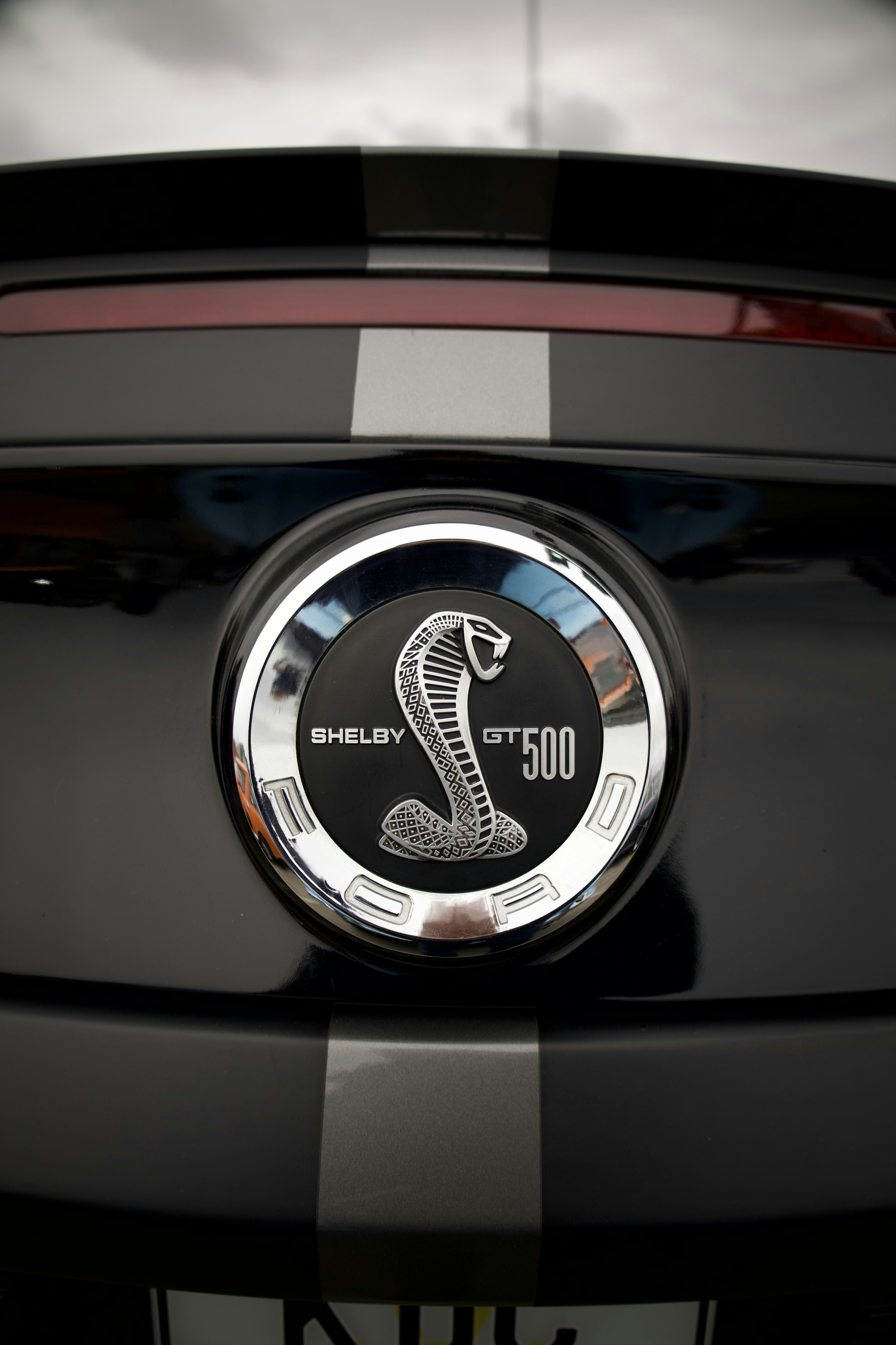 Black car with shelby gt500 emblem and racing stripes.