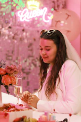 Woman wearing a veil at a festive pink celebration.