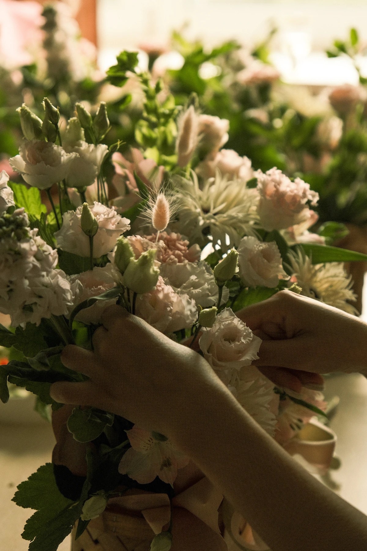 A florist arranging a fresh bouquet at a flower shop workbench