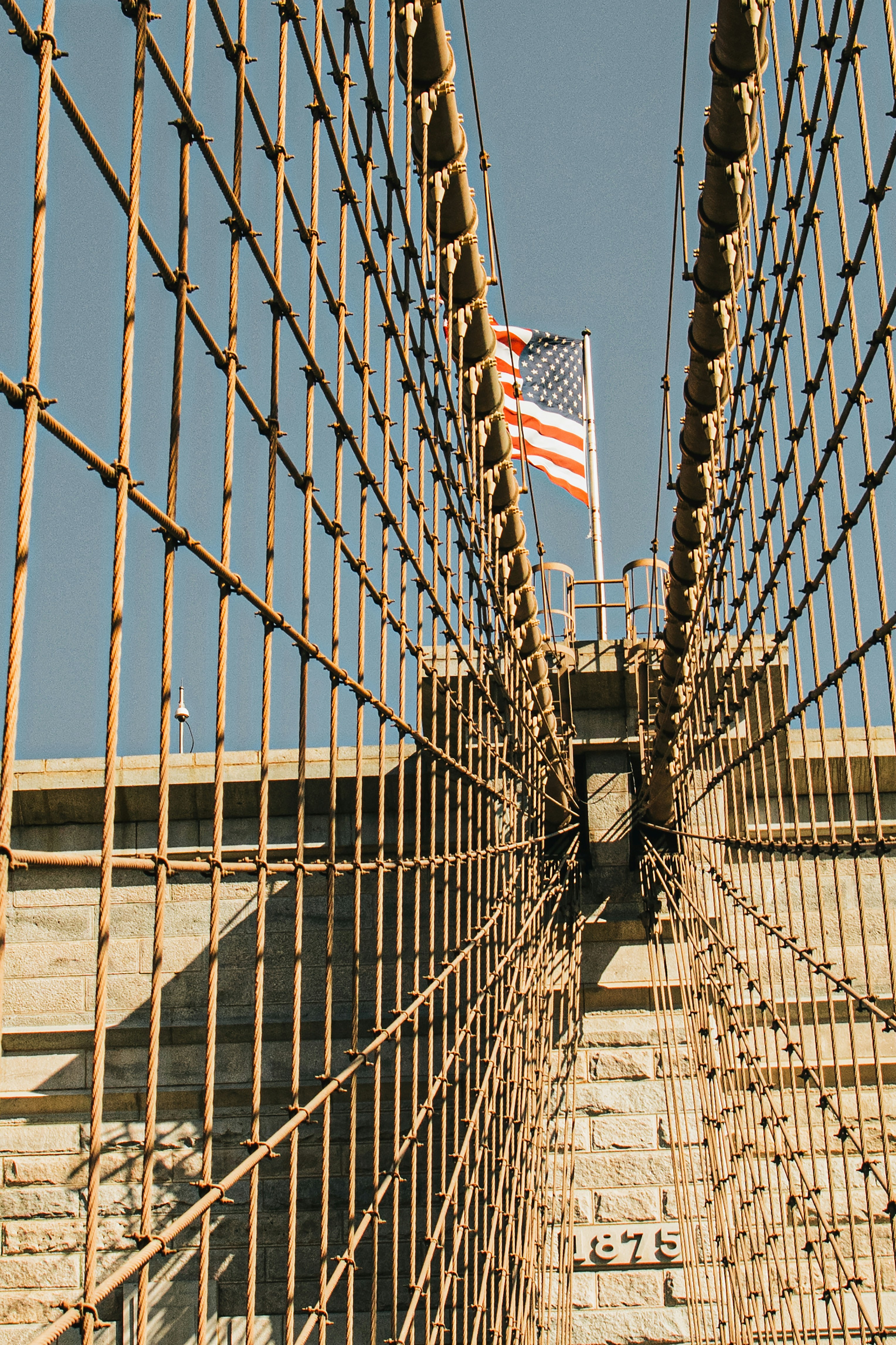 American flag flying above the brooklyn bridge cables.