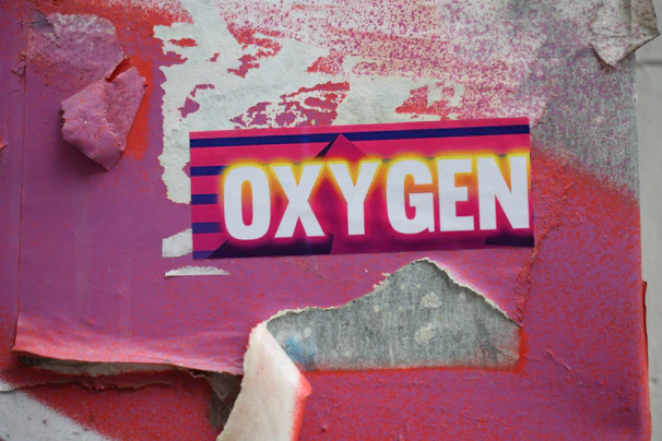 Weathered wall with "oxygen" sticker and torn pink paper.