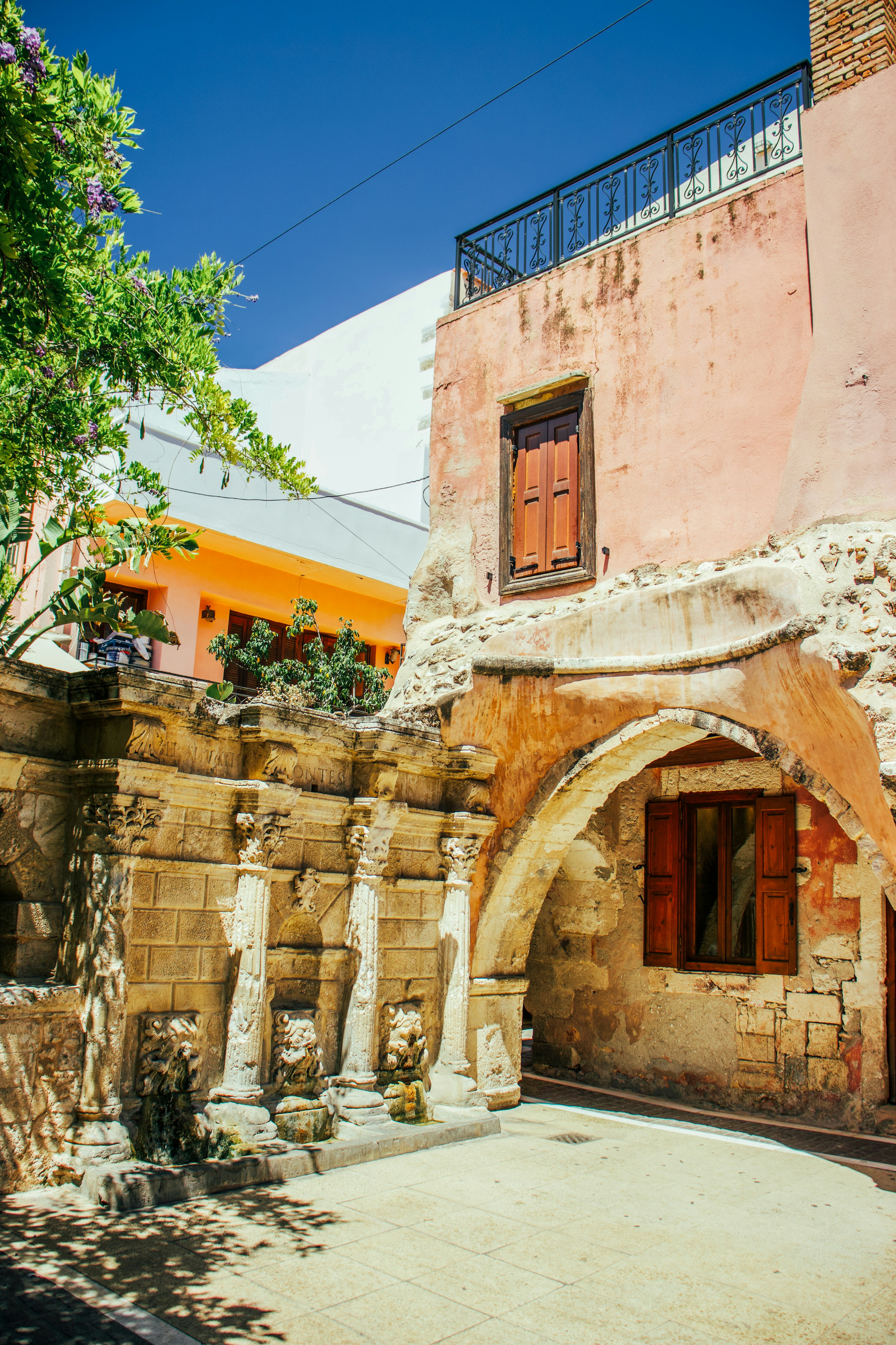 Ancient stone structure and old pink building under blue sky