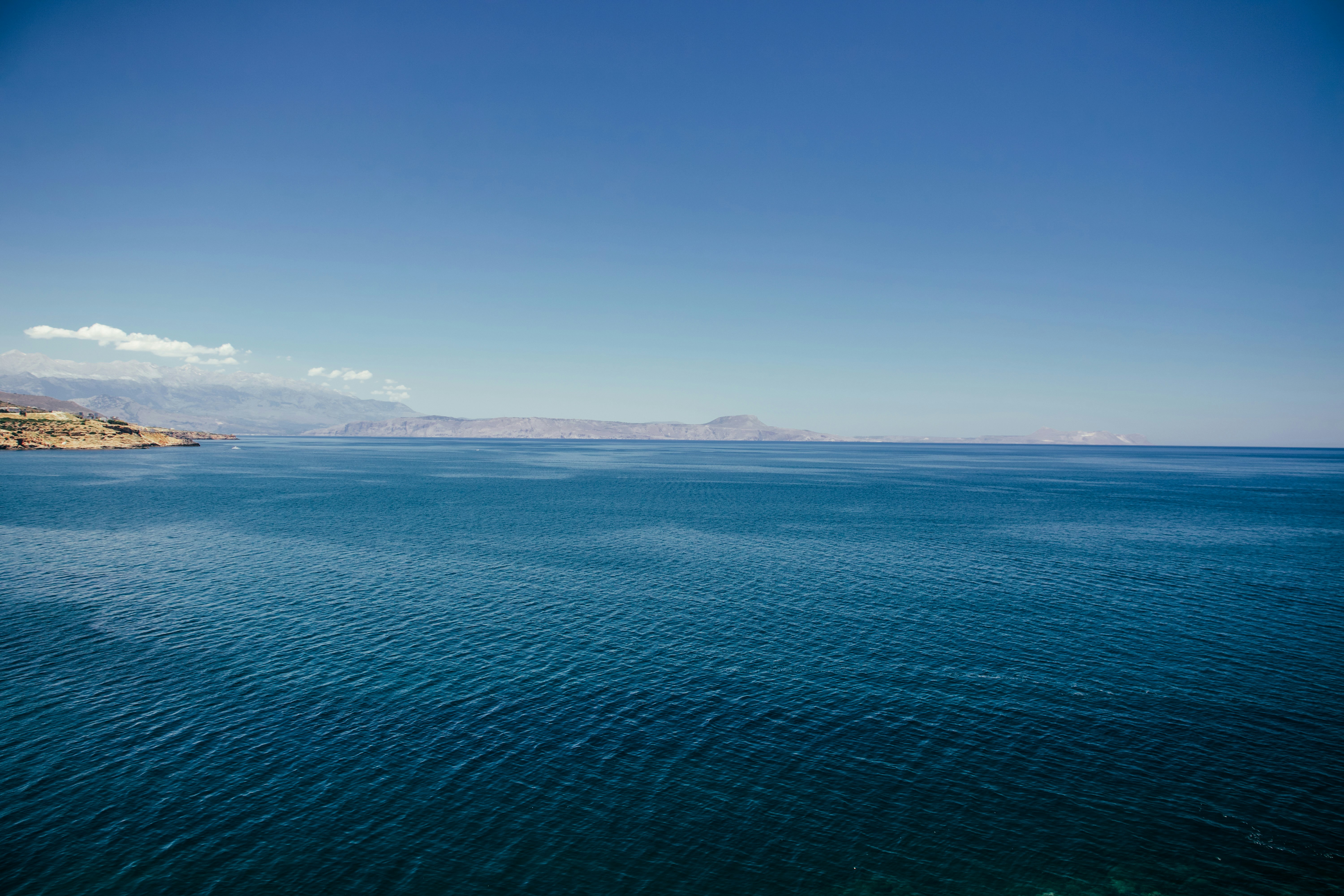 Blue ocean under clear sky with distant land