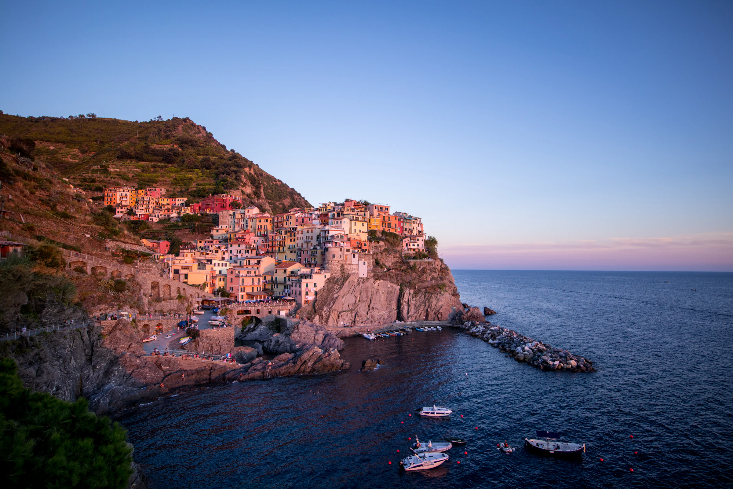 Borgo costiero mediterraneo arroccato sulle scogliere al tramonto, con il mare sullo sfondo