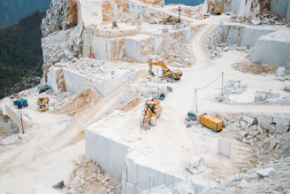 Heavy machinery works in a vast white marble quarry.