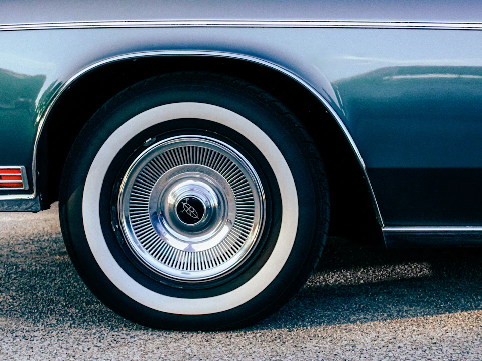 Vintage car wheel with a whitewall tire and chrome hubcap