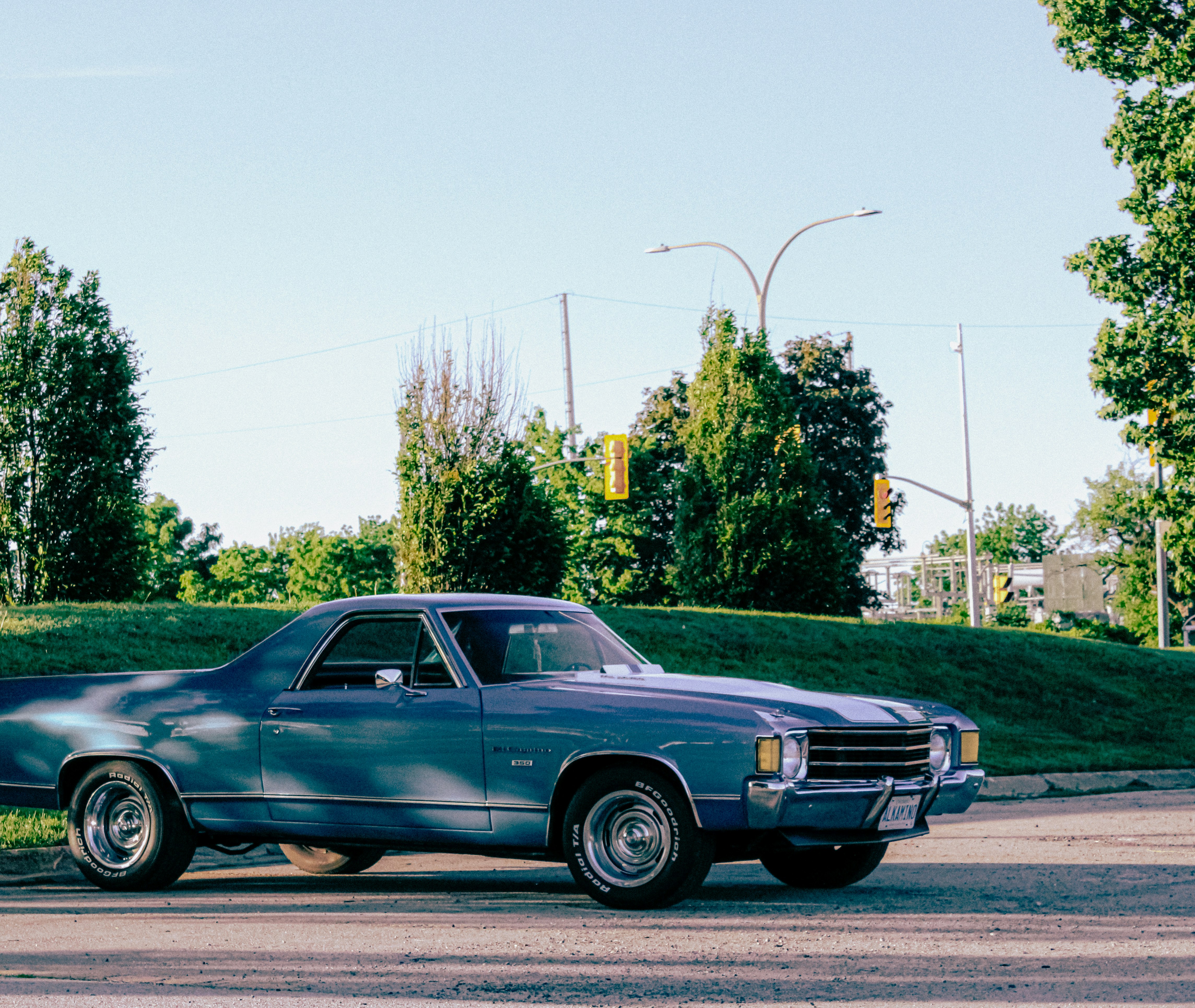 A blue classic car parked on a sunny street.