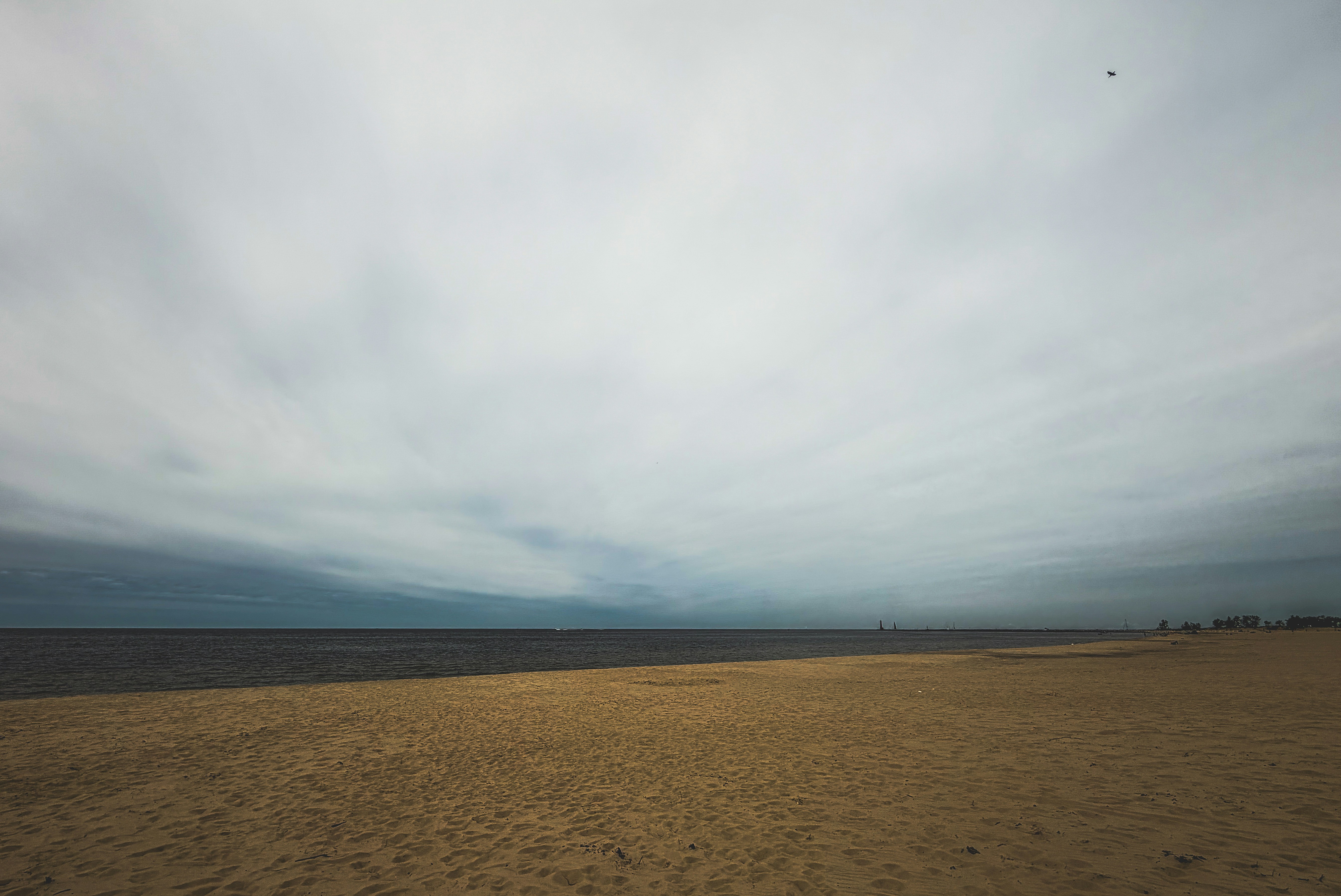 A sandy beach meets the ocean under a cloudy sky