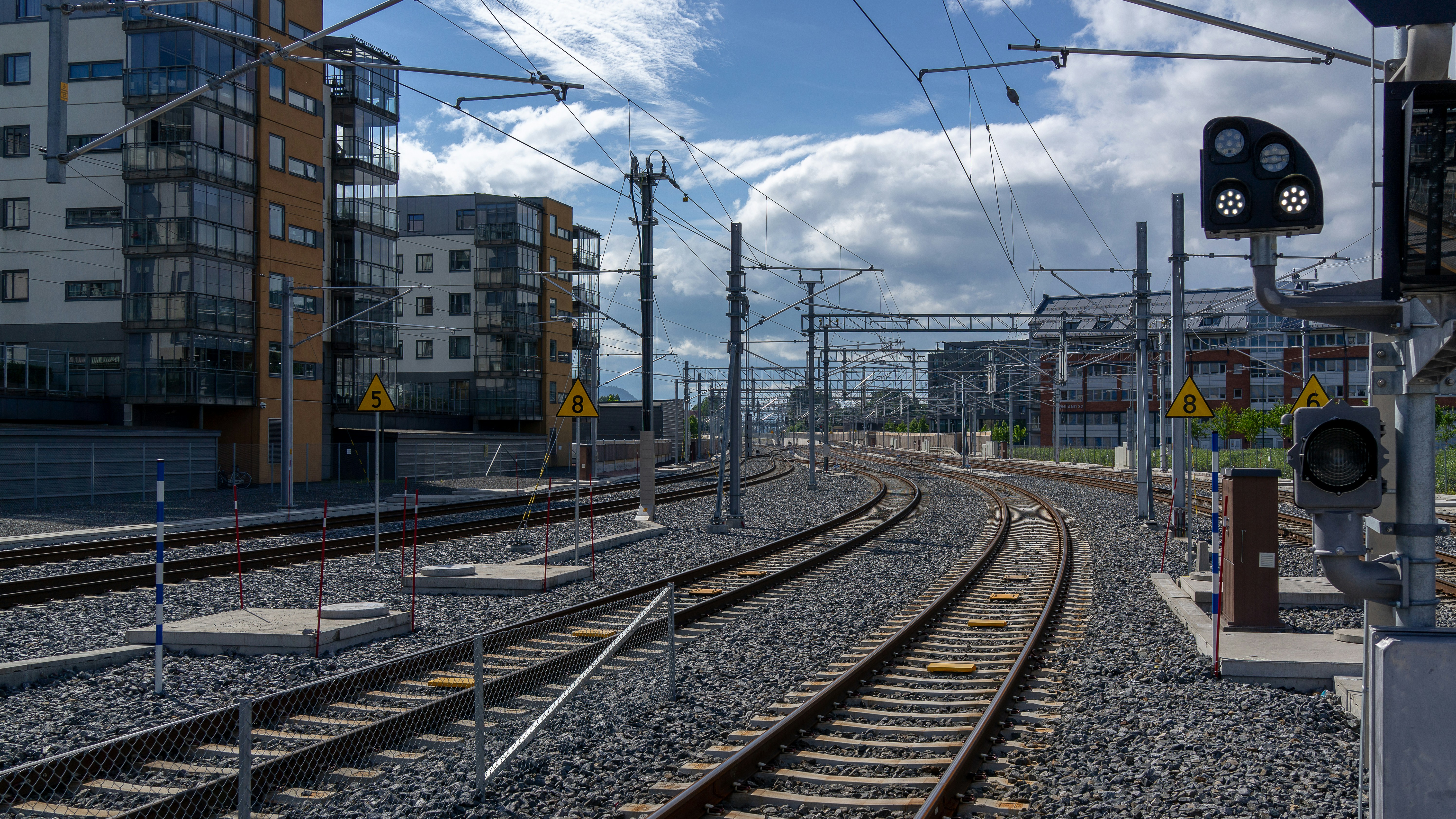 Curved railway tracks with a signal beside new apartments
