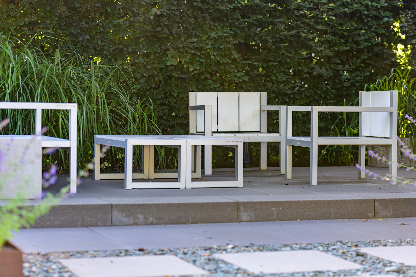 A narrow backyard gets new life from a planted perimeter, a slim dining table, and a single chair pulled to one corner.
